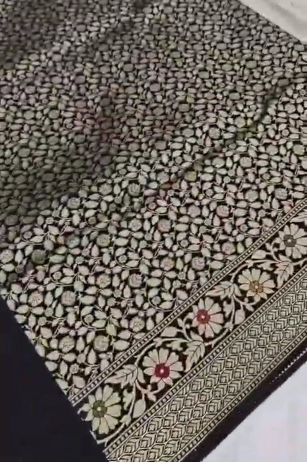A majestic black Banarasi semi Katan silk saree with a plain body, vibrant three-colored Tilfi Meenakari floral borders, and an ornate gold zari blouse.