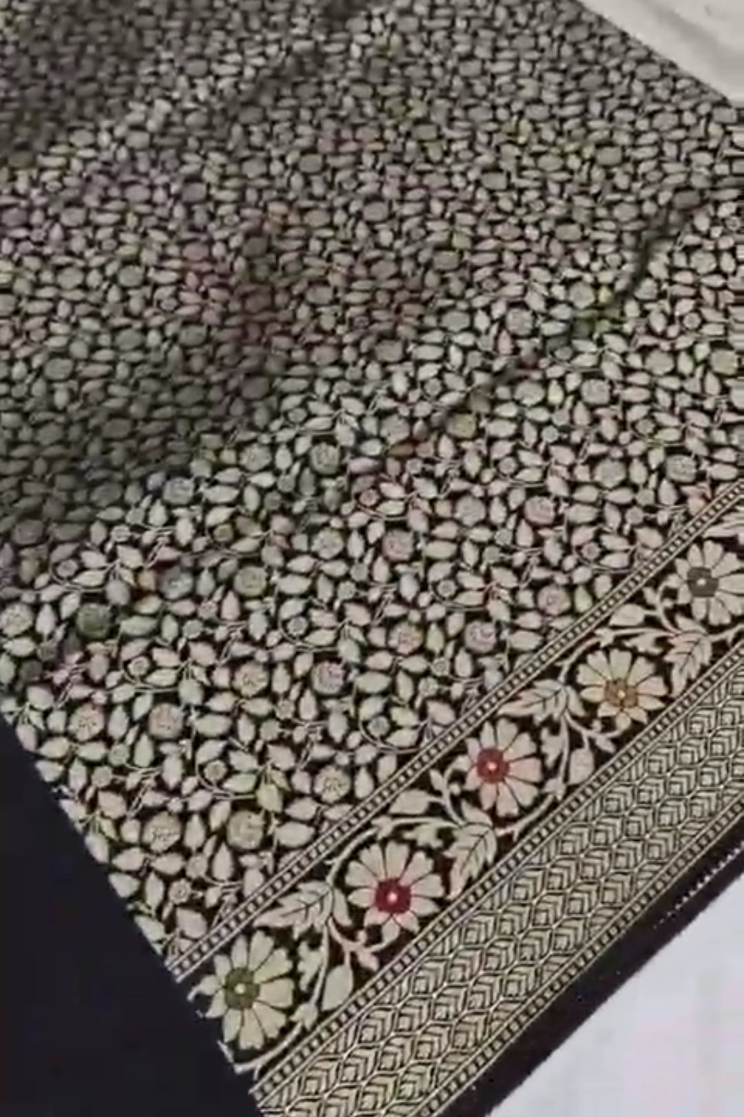 A majestic black Banarasi semi Katan silk saree with a plain body, vibrant three-colored Tilfi Meenakari floral borders, and an ornate gold zari blouse.