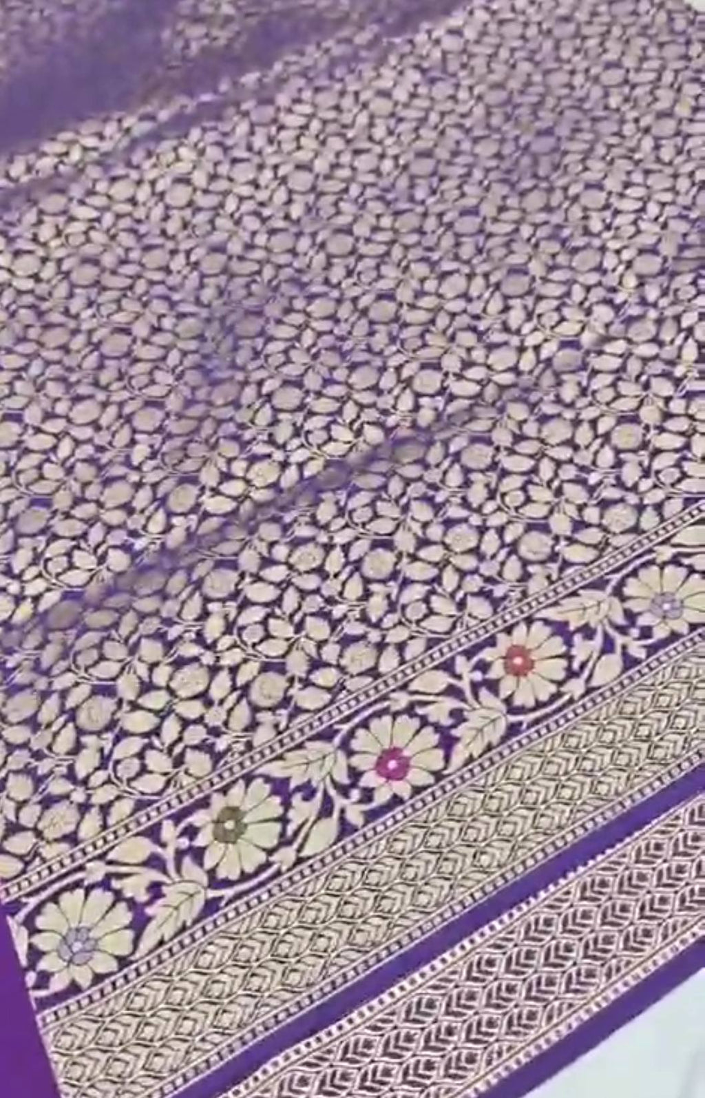 A soft lilac Banarasi semi Katan silk saree with a minimalist plain body, intricate multi-colored Tilfi Meenakari floral borders, and a matching gold zari brocade blouse.