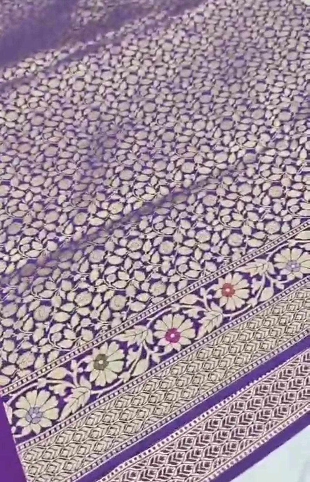 A soft lilac Banarasi semi Katan silk saree with a minimalist plain body, intricate multi-colored Tilfi Meenakari floral borders, and a matching gold zari brocade blouse.