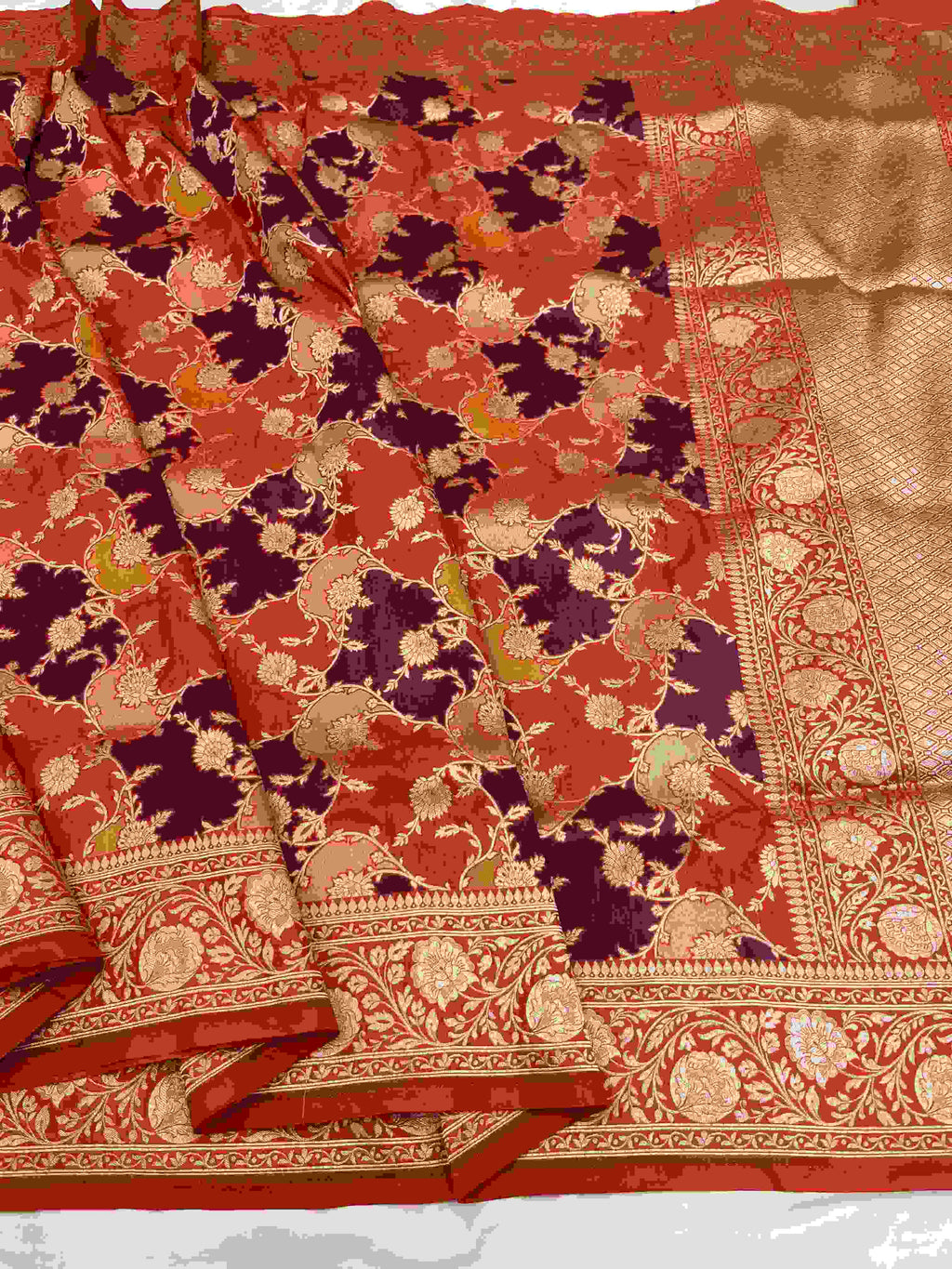 A vibrant chilly red Banarasi Katan silk saree featuring rare Rangkaat diagonal color blocking and multi-hued Meenakari floral weaving.