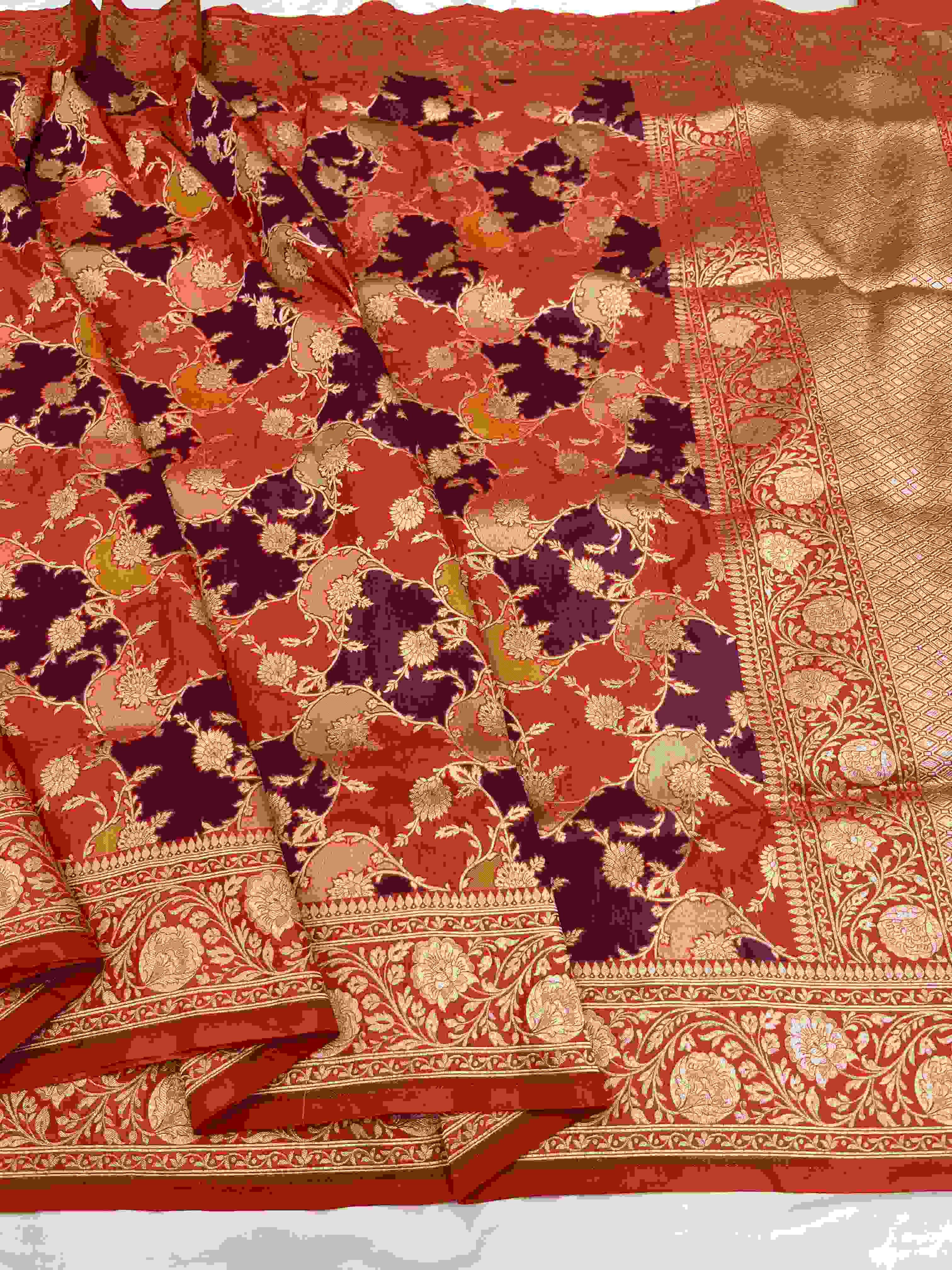 A vibrant chilly red Banarasi Katan silk saree featuring rare Rangkaat diagonal color blocking and multi-hued Meenakari floral weaving.