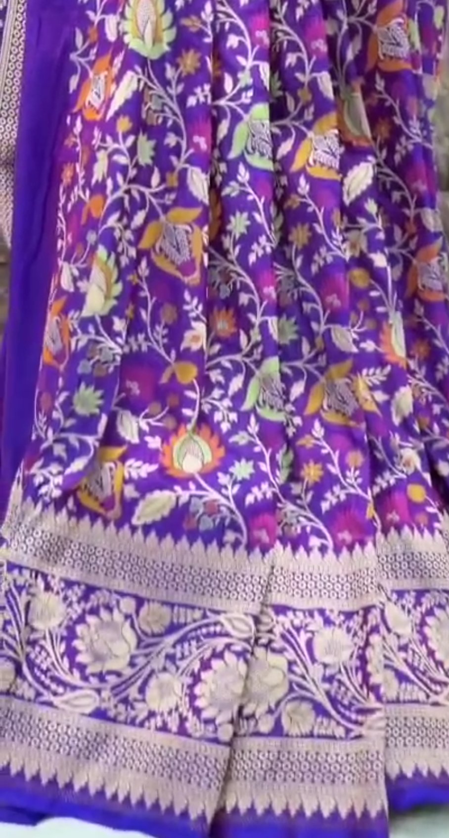 A deep purple Banarasi Katan silk saree featuring vibrant three-colored Tilfi Meenakari floral buttas and an ornate gold zari border.