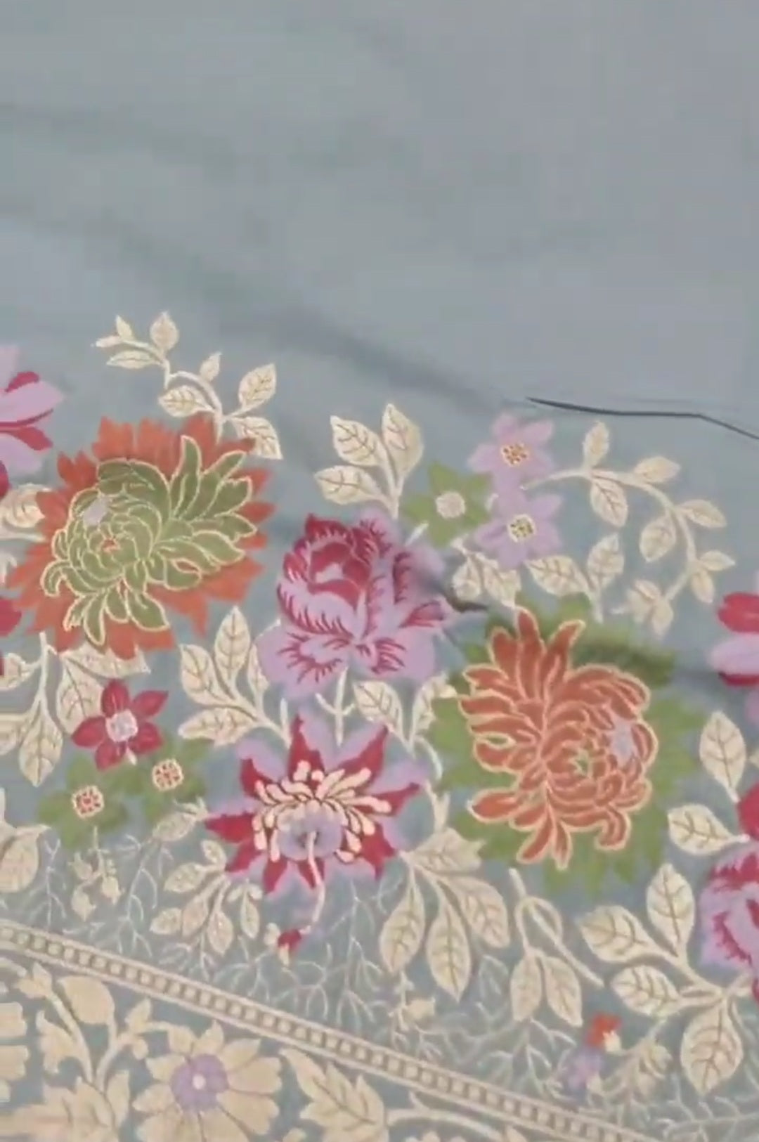 A serene powder blue Banarasi semi Katan silk saree with a plain body, a multi-colored Tilfi Meenakari floral border, and a matching heavy brocade blouse.