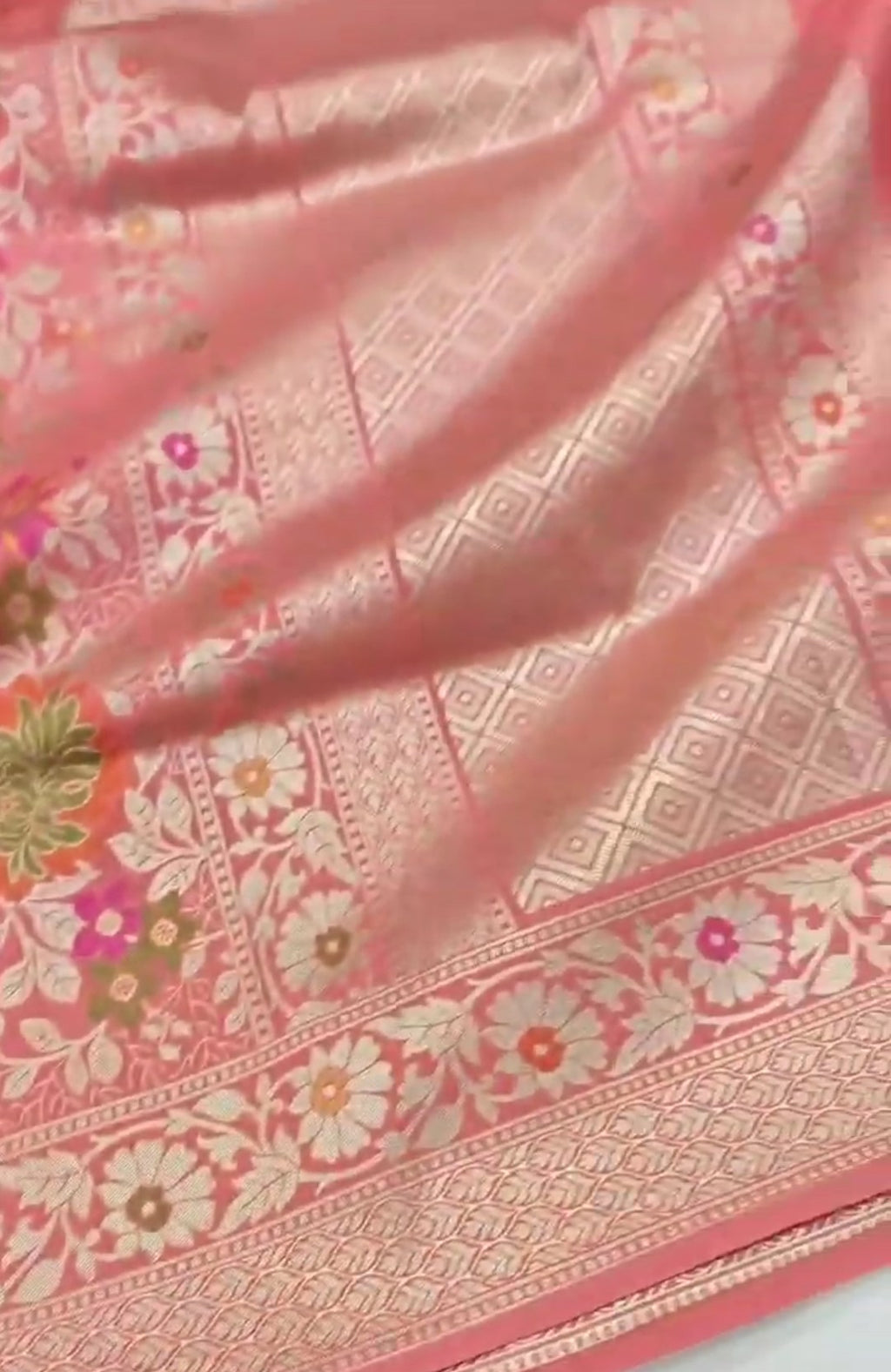 A soft peach Banarasi semi Katan silk saree with a plain body, featuring a multi-colored Tilfi Meenakari floral border and a matching full brocade blouse piece.