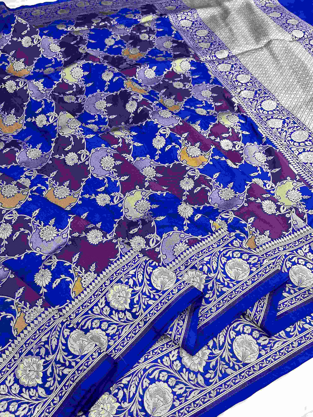 A deep azure blue Banarasi Katan silk saree featuring hand-woven Rangkaat diagonal color blocks and intricate Meenakari floral vines in gold zari.