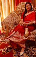 A vibrant red Banarasi Katan silk saree with a handloom-woven Kashi Ghat temple motif border in gold and silver zari with Meenakari accents.