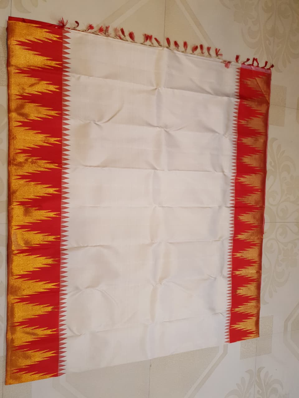 Beige Kanchipuram Handloom Silk Saree with a red Korvai temple border and 2G gold zari motifs in a South Indian temple setting.