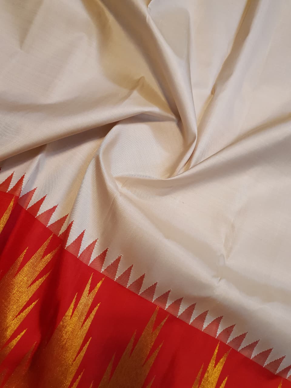 Beige Kanchipuram Handloom Silk Saree with a red Korvai temple border and 2G gold zari motifs in a South Indian temple setting.