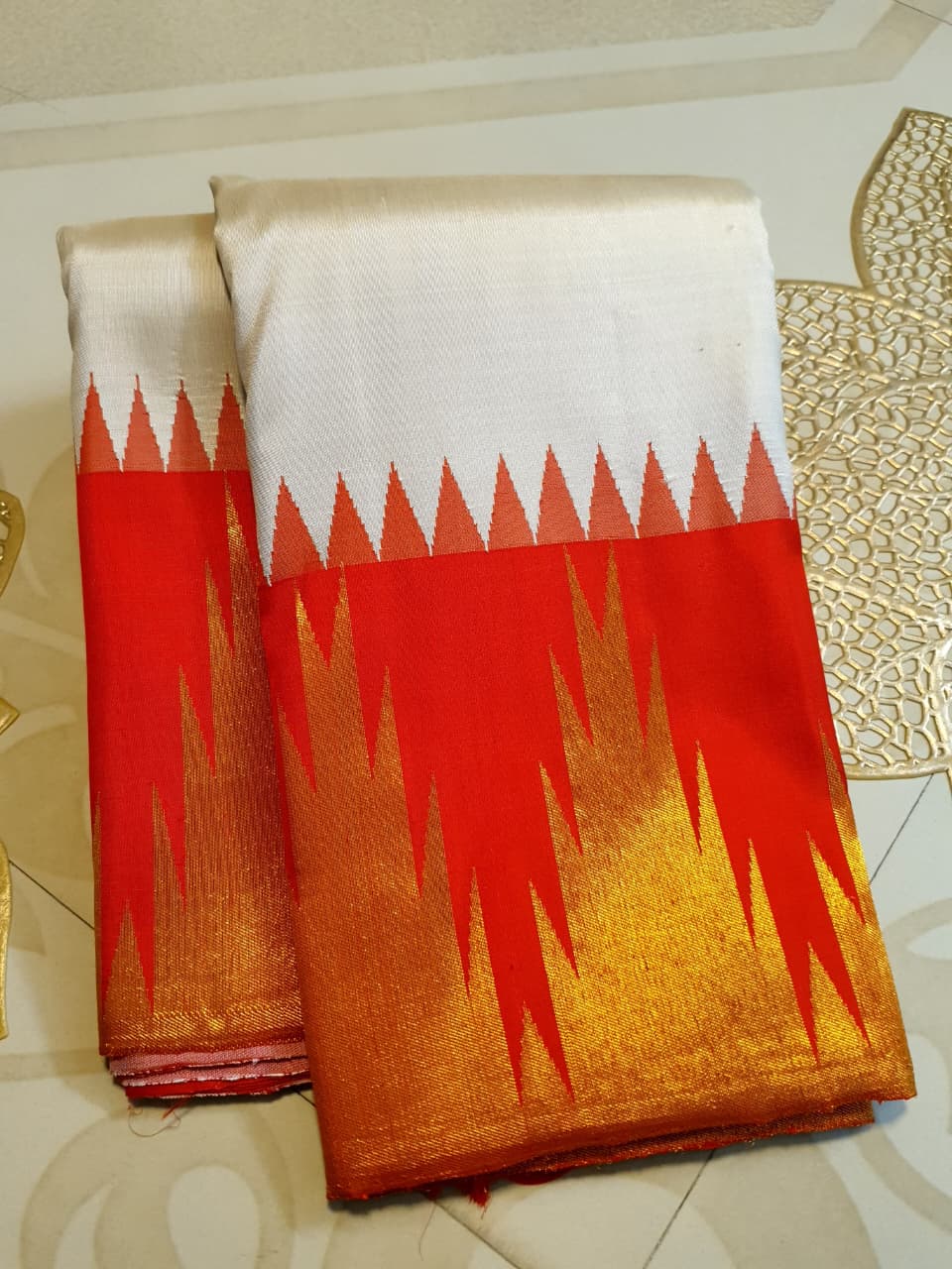 Beige Kanchipuram Handloom Silk Saree with a red Korvai temple border and 2G gold zari motifs in a South Indian temple setting.