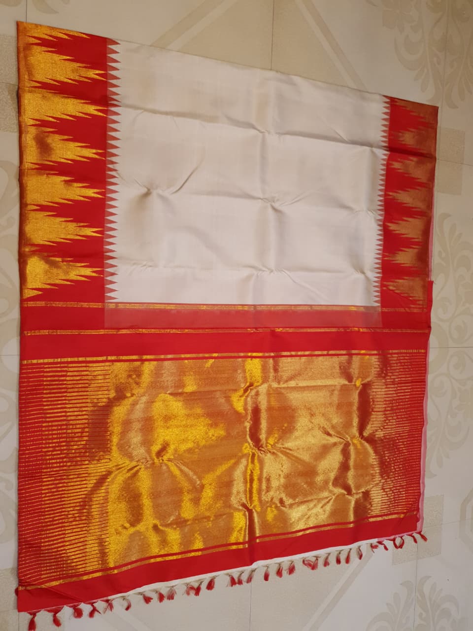 Beige Kanchipuram Handloom Silk Saree with a red Korvai temple border and 2G gold zari motifs in a South Indian temple setting.