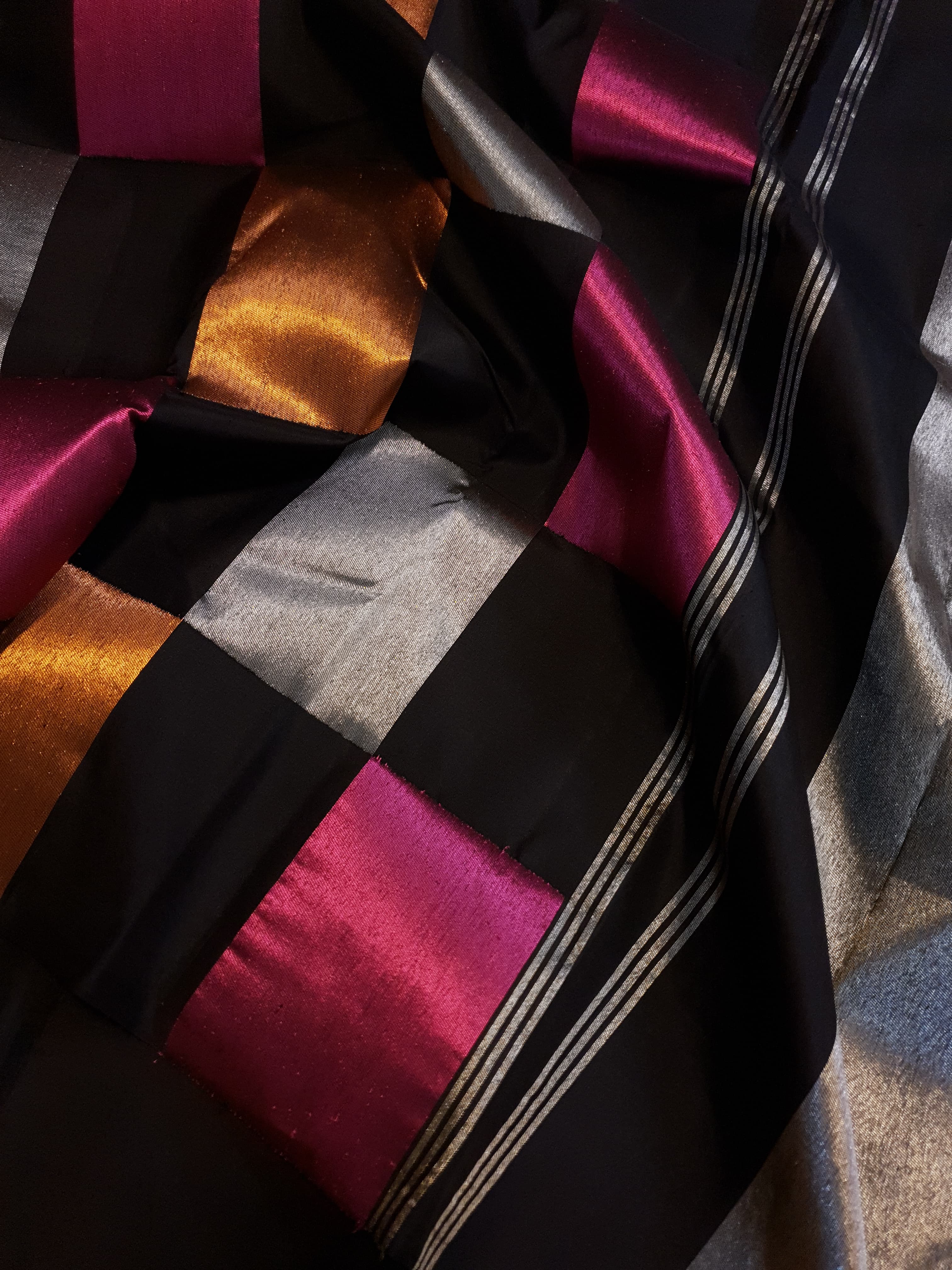 A luxurious multicolor 2G Kanchipuram pattu silk saree featuring a bold checkered pattern in black, pink, gold, and silver, displayed elegantly with traditional weaves.