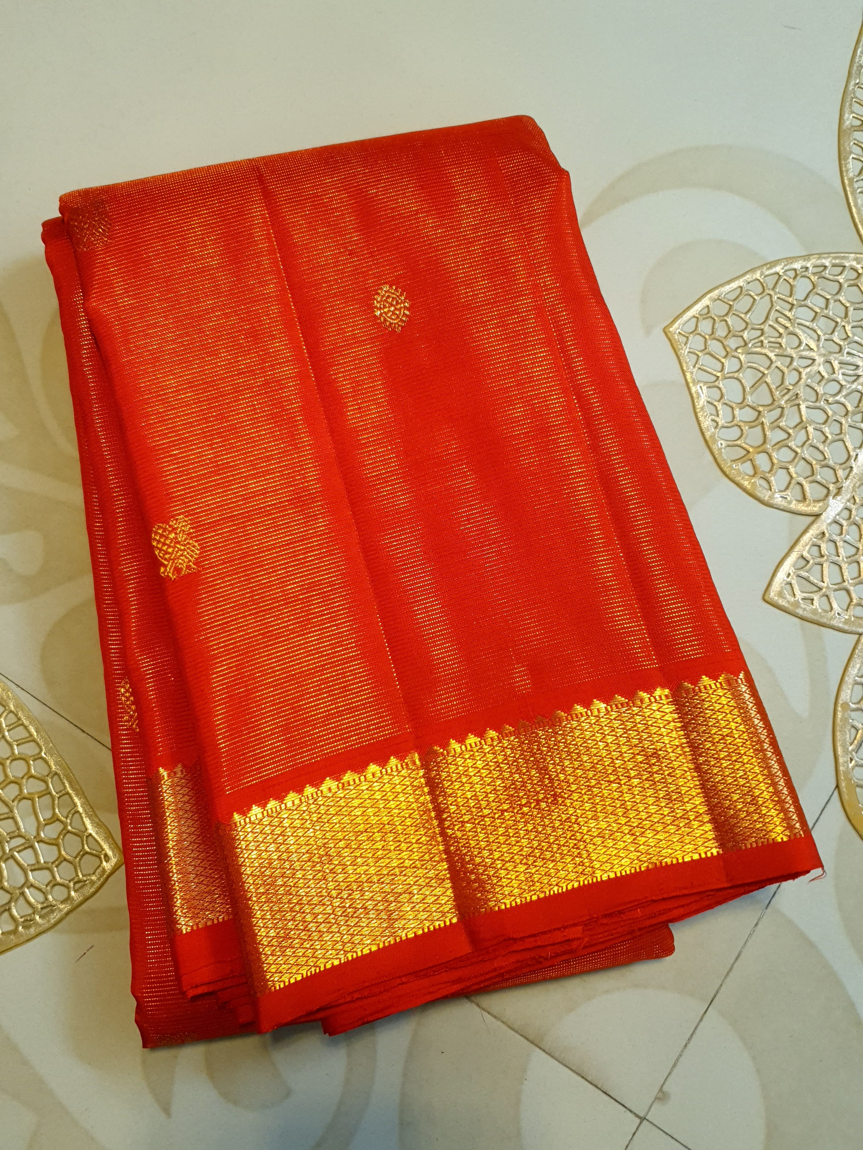 Vibrant Chilly Red Kanjivaram silk saree with a traditional gold zari border and small buttis.