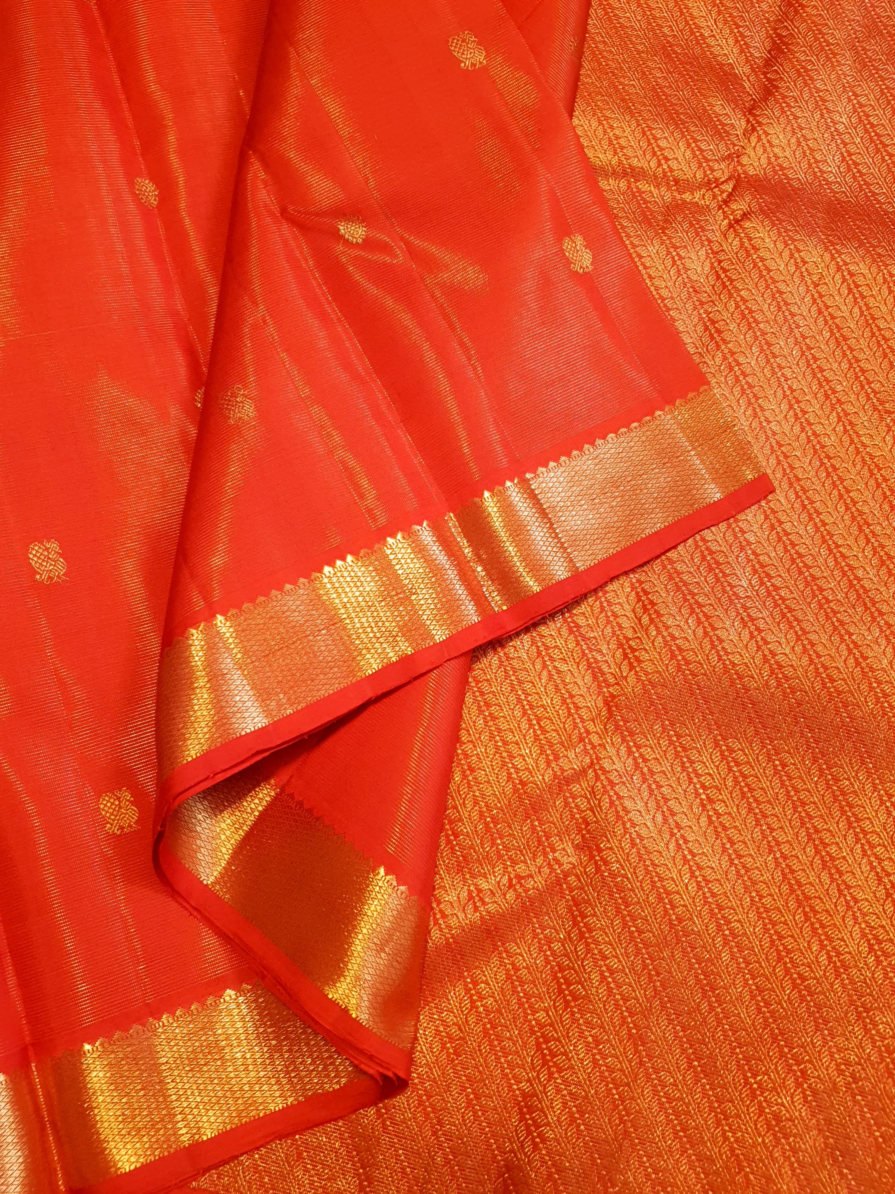 Vibrant Chilly Red Kanjivaram silk saree with a traditional gold zari border and small buttis.