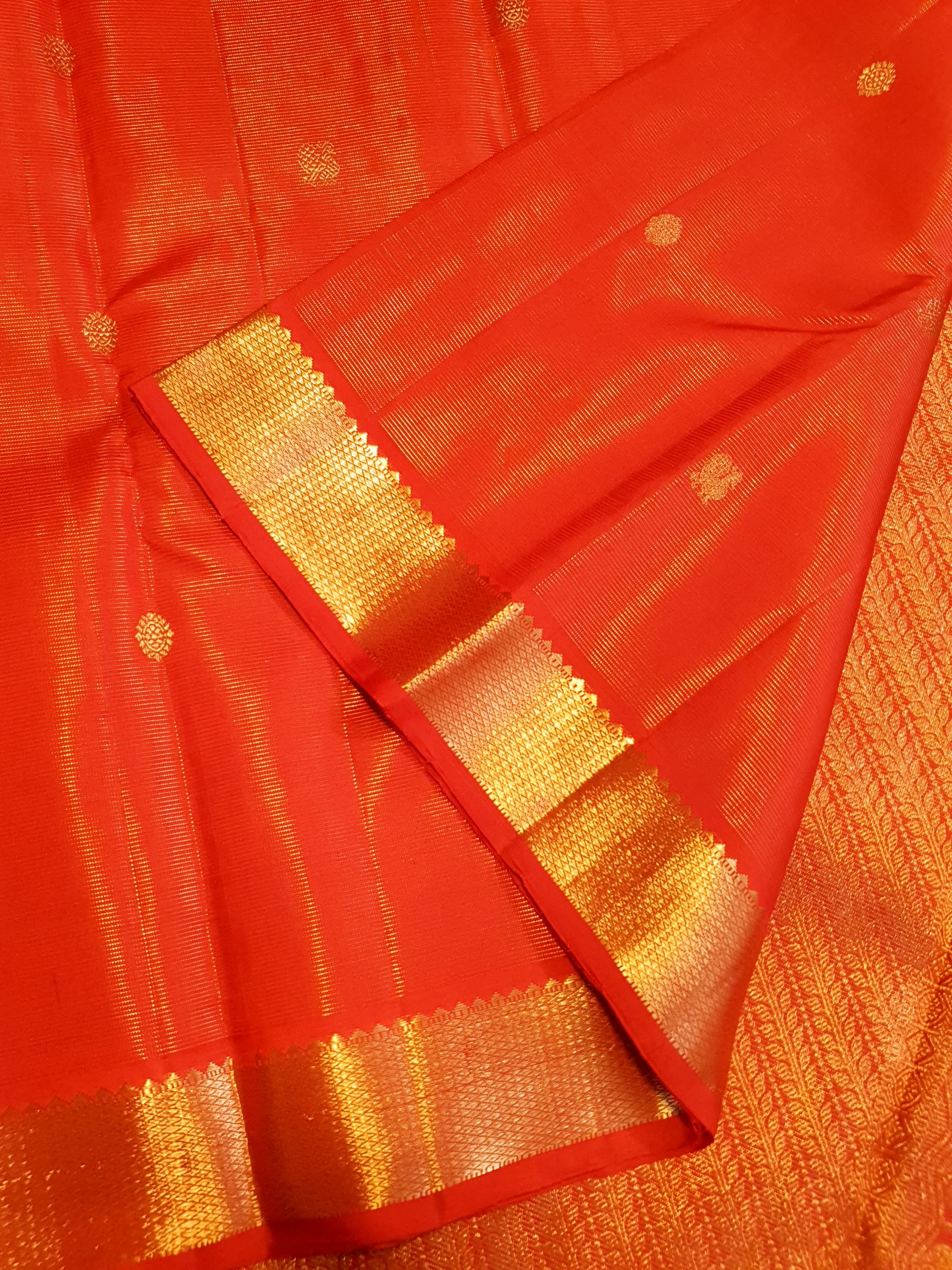 Vibrant Chilly Red Kanjivaram silk saree with a traditional gold zari border and small buttis.