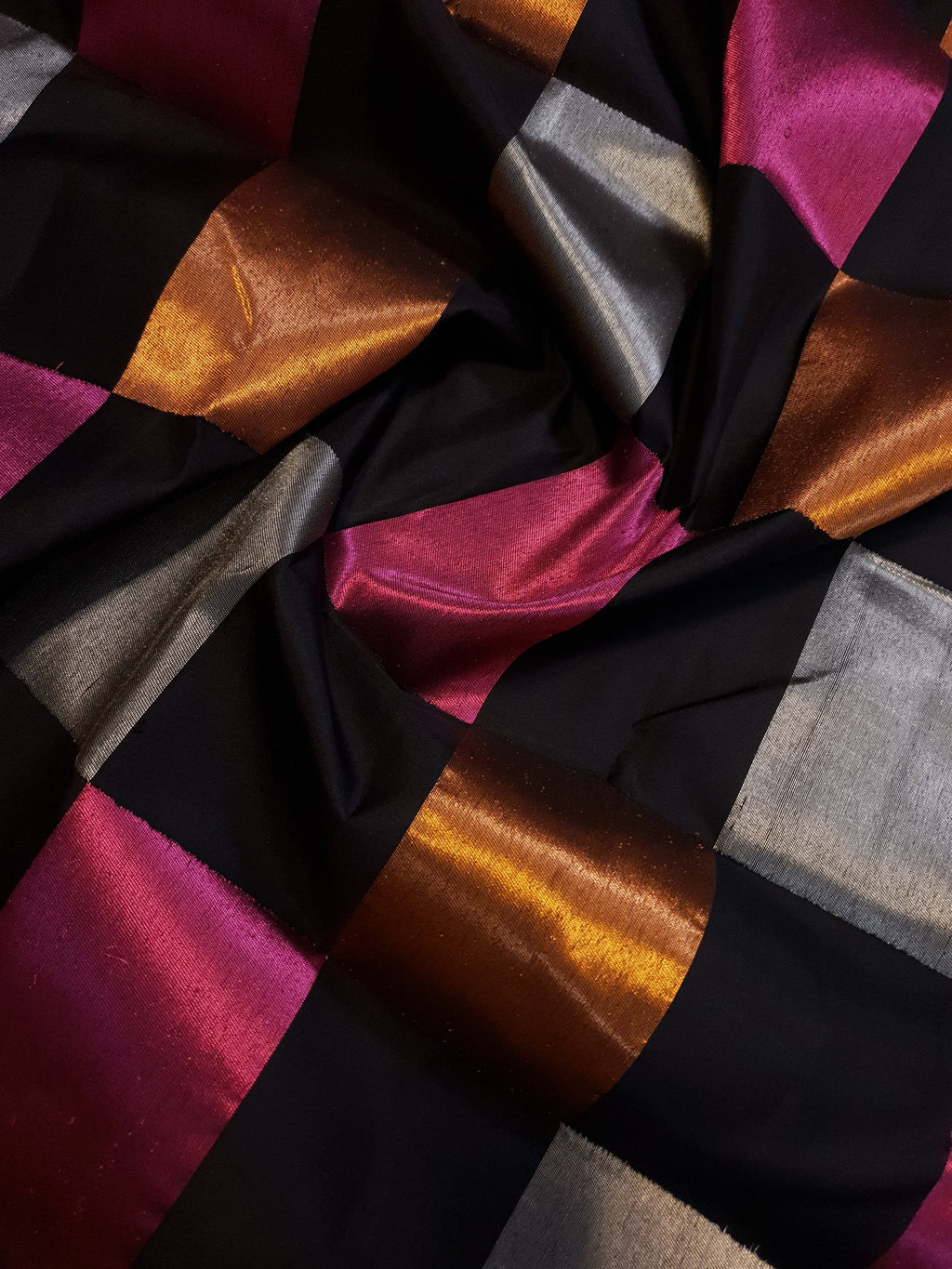 A luxurious multicolor 2G Kanchipuram pattu silk saree featuring a bold checkered pattern in black, pink, gold, and silver, displayed elegantly with traditional weaves.