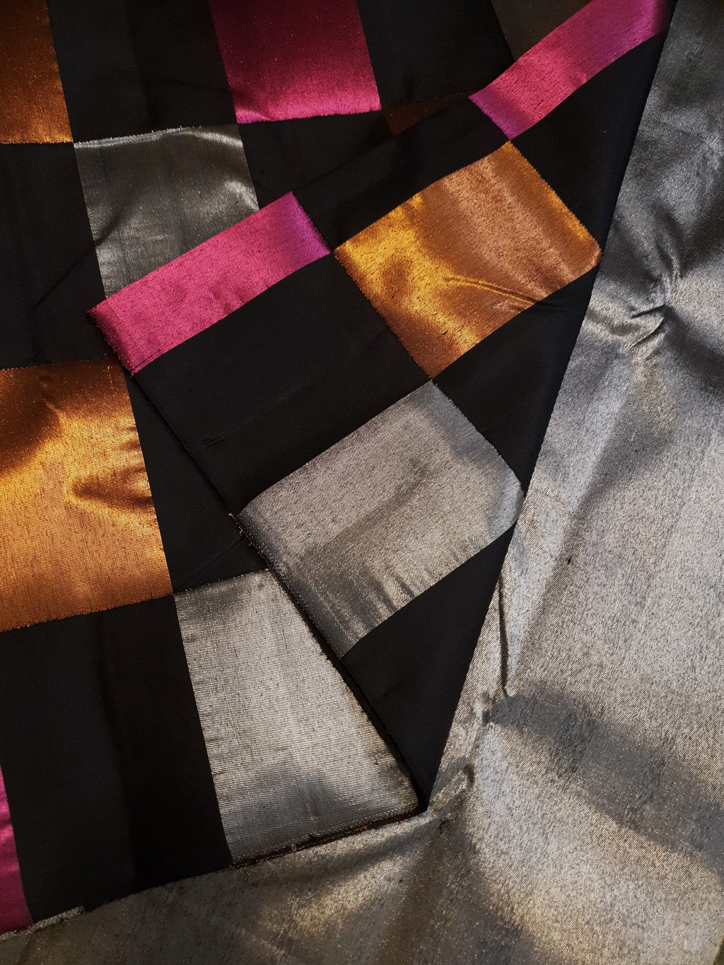 A luxurious multicolor 2G Kanchipuram pattu silk saree featuring a bold checkered pattern in black, pink, gold, and silver, displayed elegantly with traditional weaves.