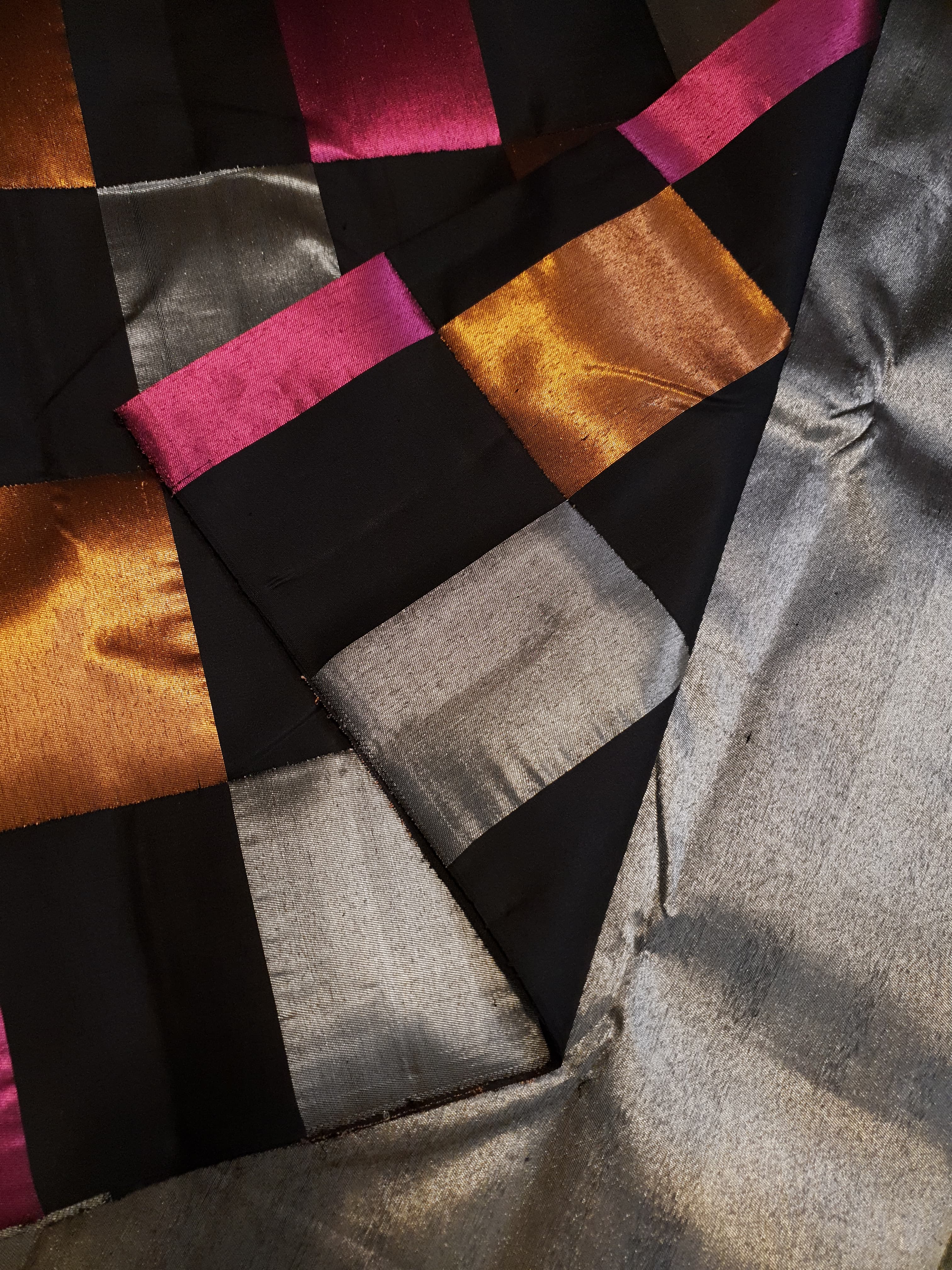 A luxurious multicolor 2G Kanchipuram pattu silk saree featuring a bold checkered pattern in black, pink, gold, and silver, displayed elegantly with traditional weaves.