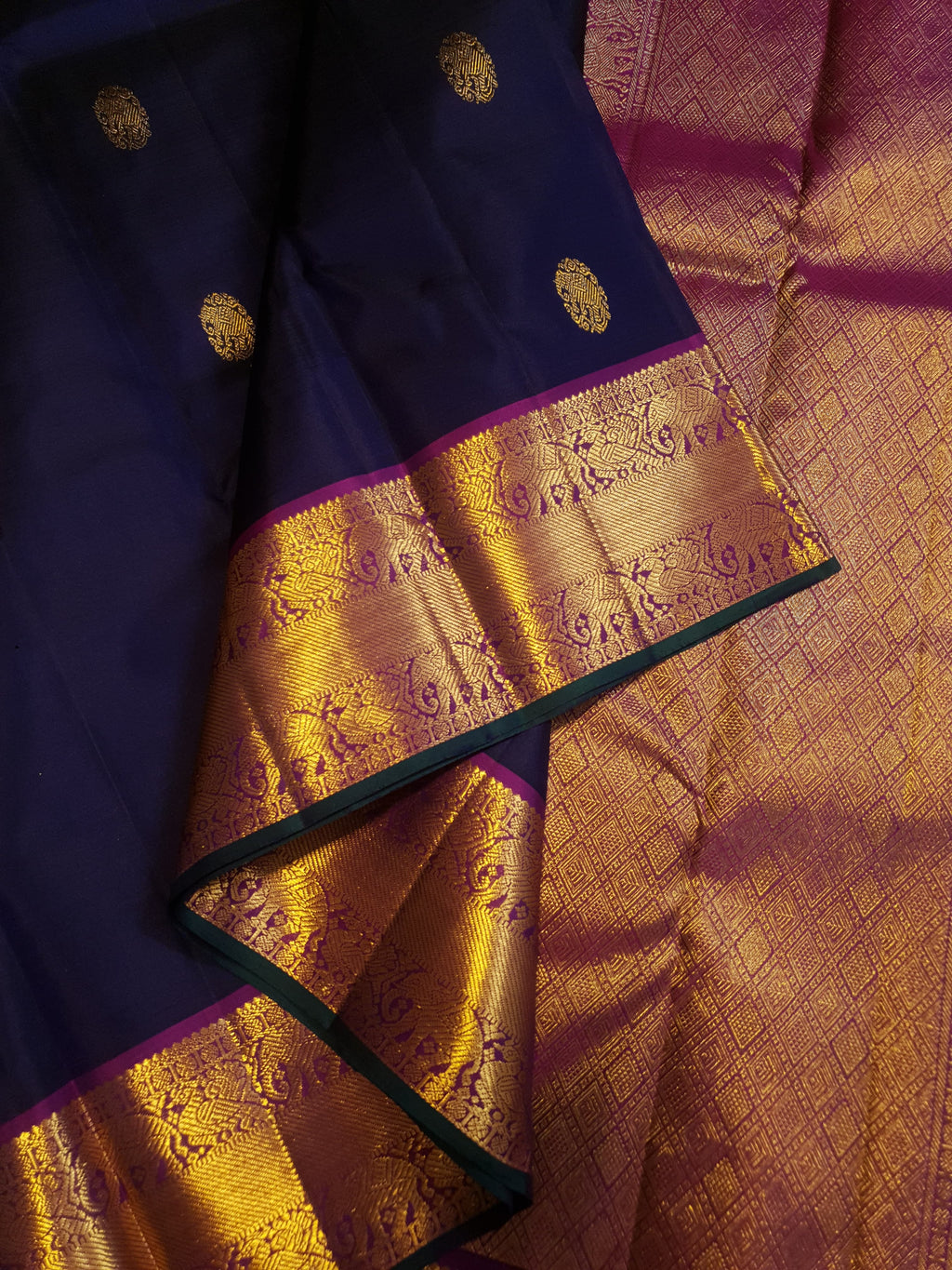 Midnight blue Kanchipuram handloom silk saree, featuring a rich gold zari border and intricate traditional gold motifs.