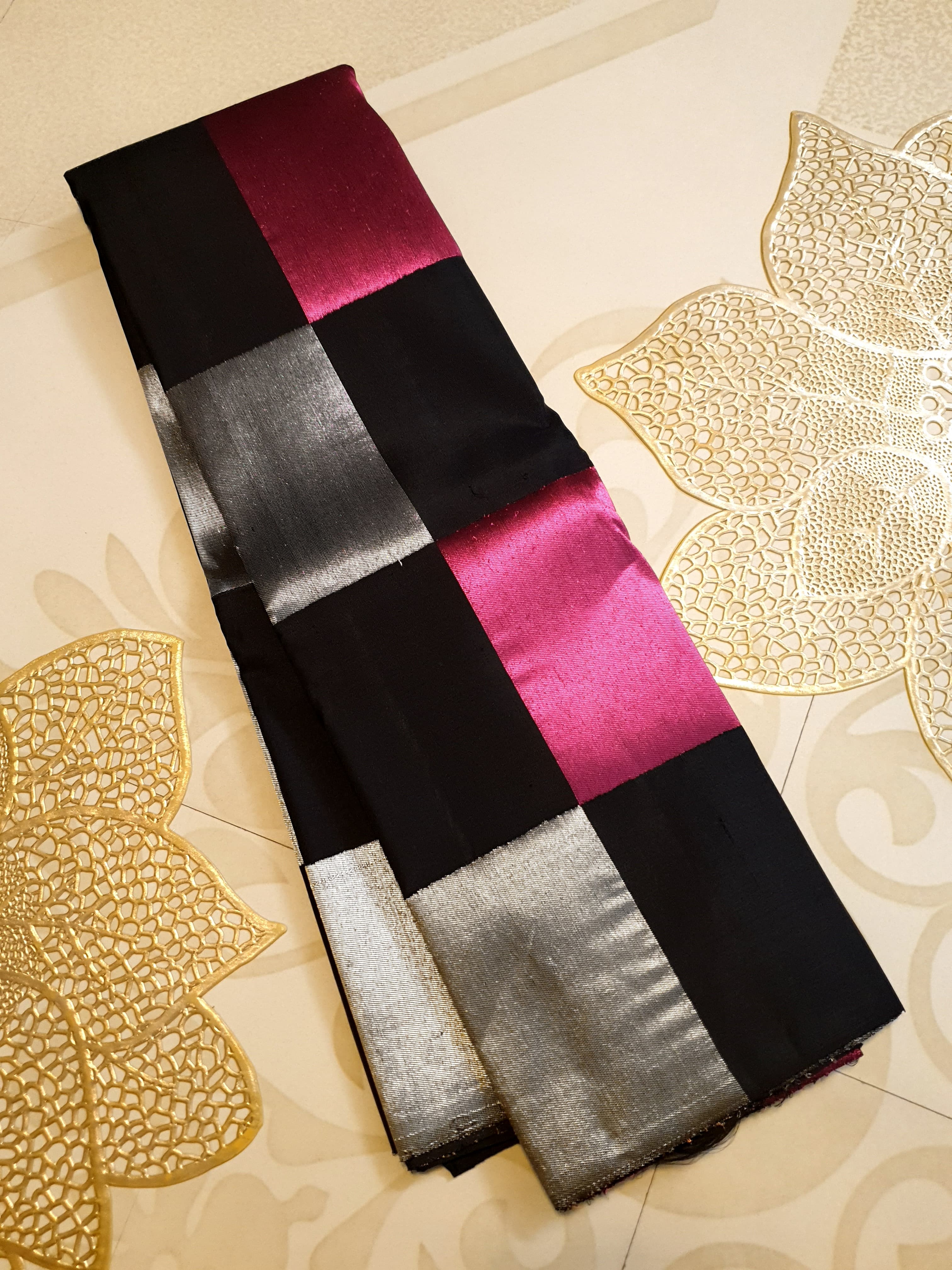 A luxurious multicolor 2G Kanchipuram pattu silk saree featuring a bold checkered pattern in black, pink, gold, and silver, displayed elegantly with traditional weaves.