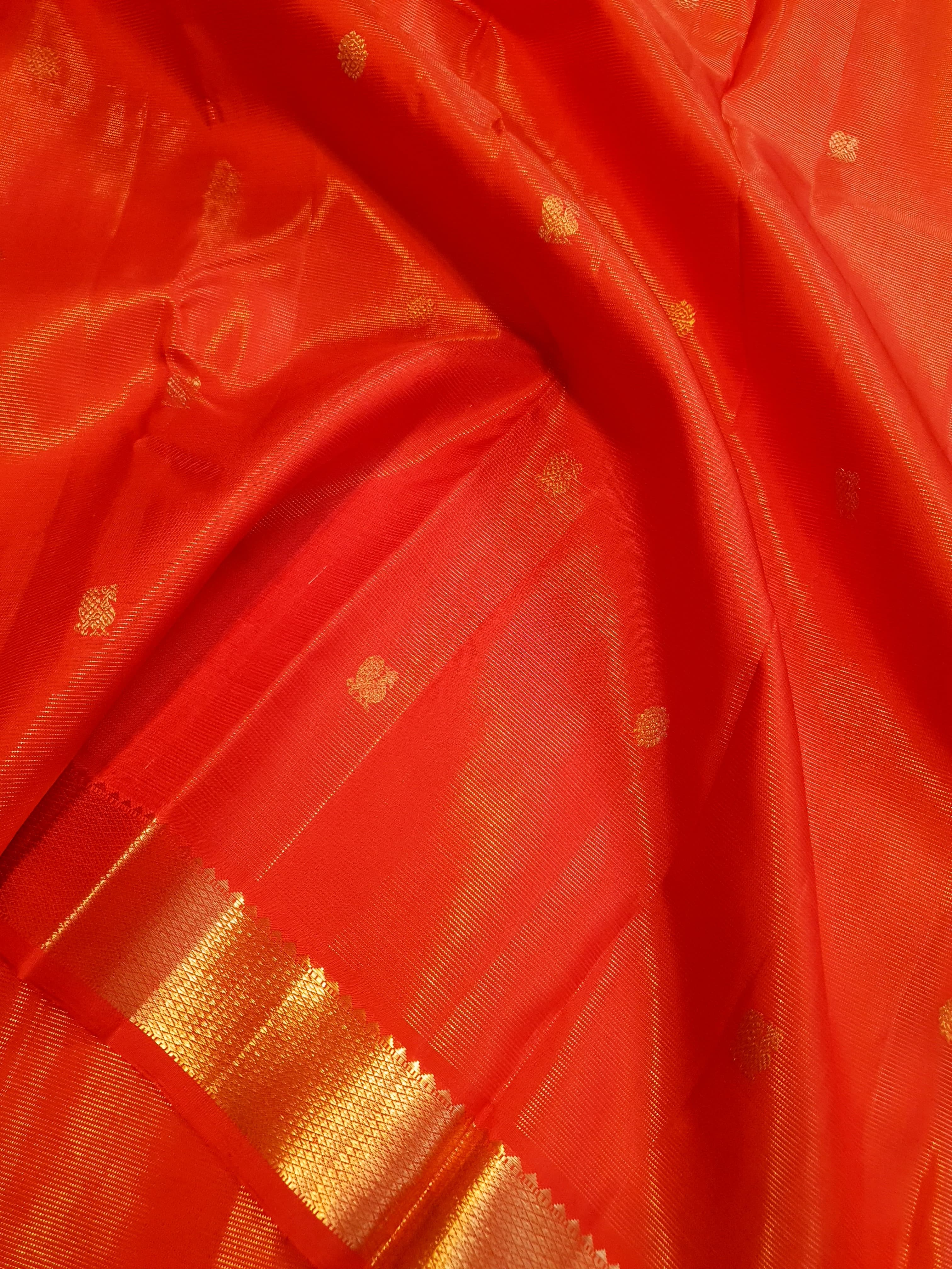 Vibrant Chilly Red Kanjivaram silk saree with a traditional gold zari border and small buttis.