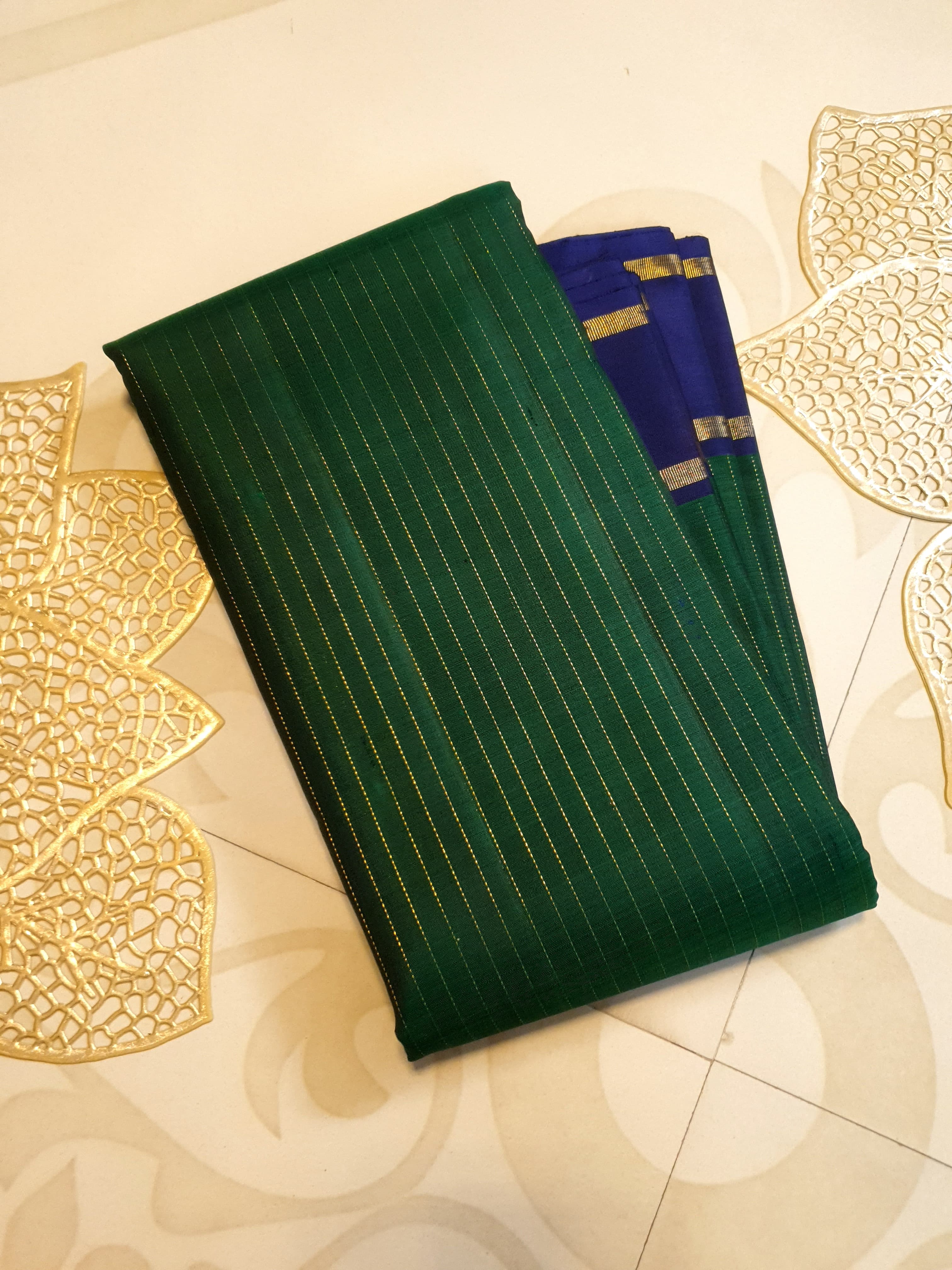 Bottle Green Kanjivaram silk saree featuring fine gold zari stripes and a contrasting royal blue border with large circular motifs.