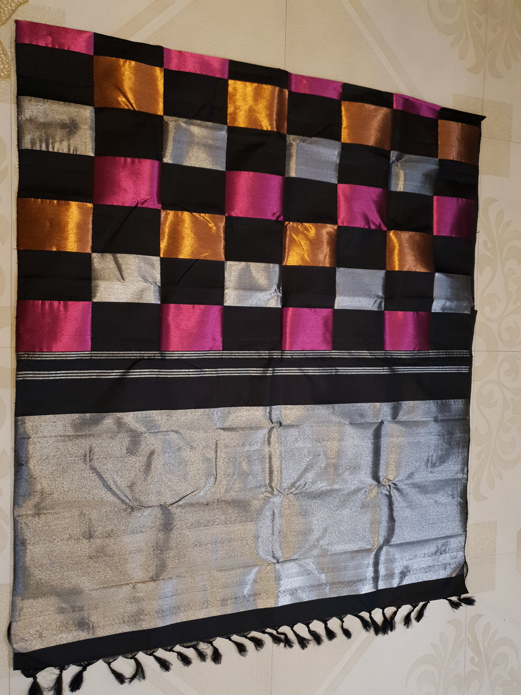 A luxurious multicolor 2G Kanchipuram pattu silk saree featuring a bold checkered pattern in black, pink, gold, and silver, displayed elegantly with traditional weaves.