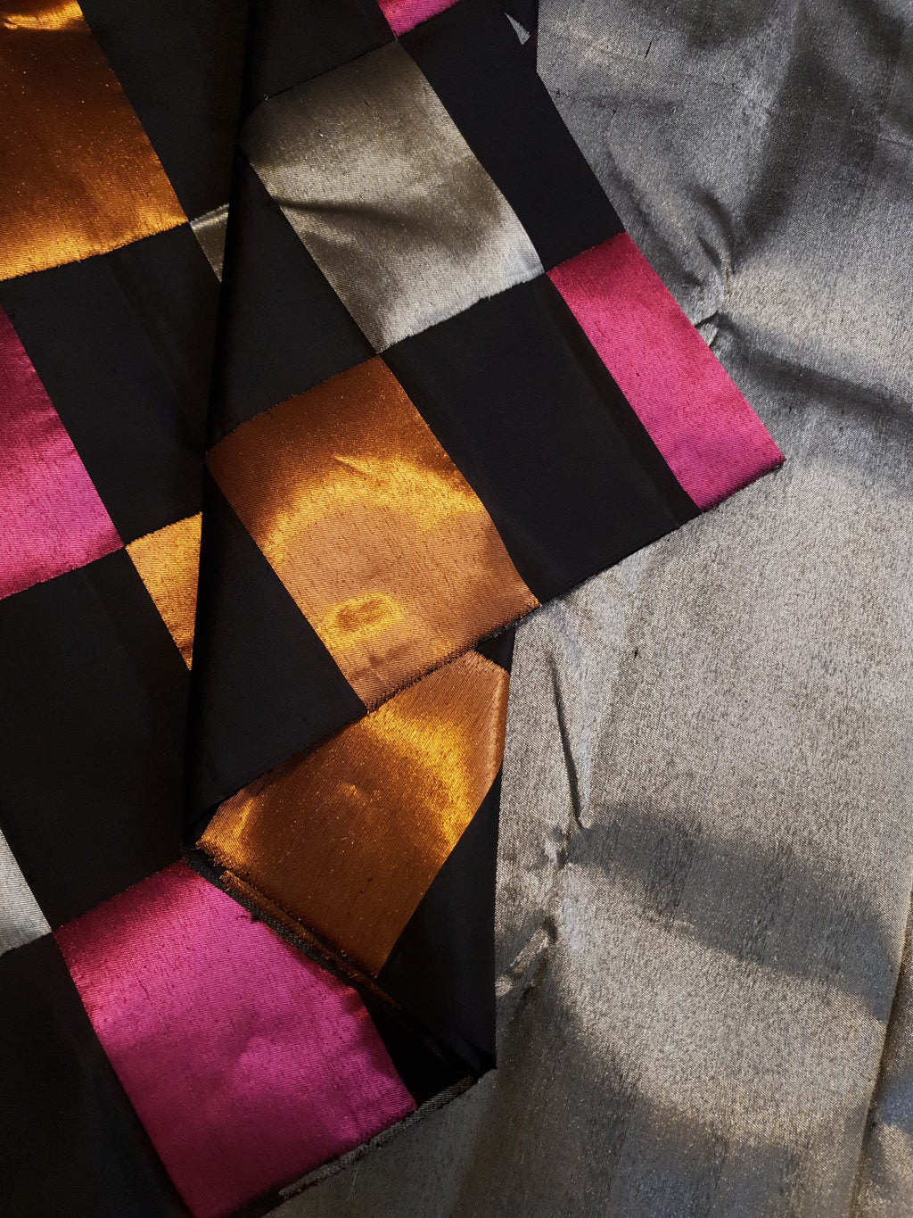 A luxurious multicolor 2G Kanchipuram pattu silk saree featuring a bold checkered pattern in black, pink, gold, and silver, displayed elegantly with traditional weaves.