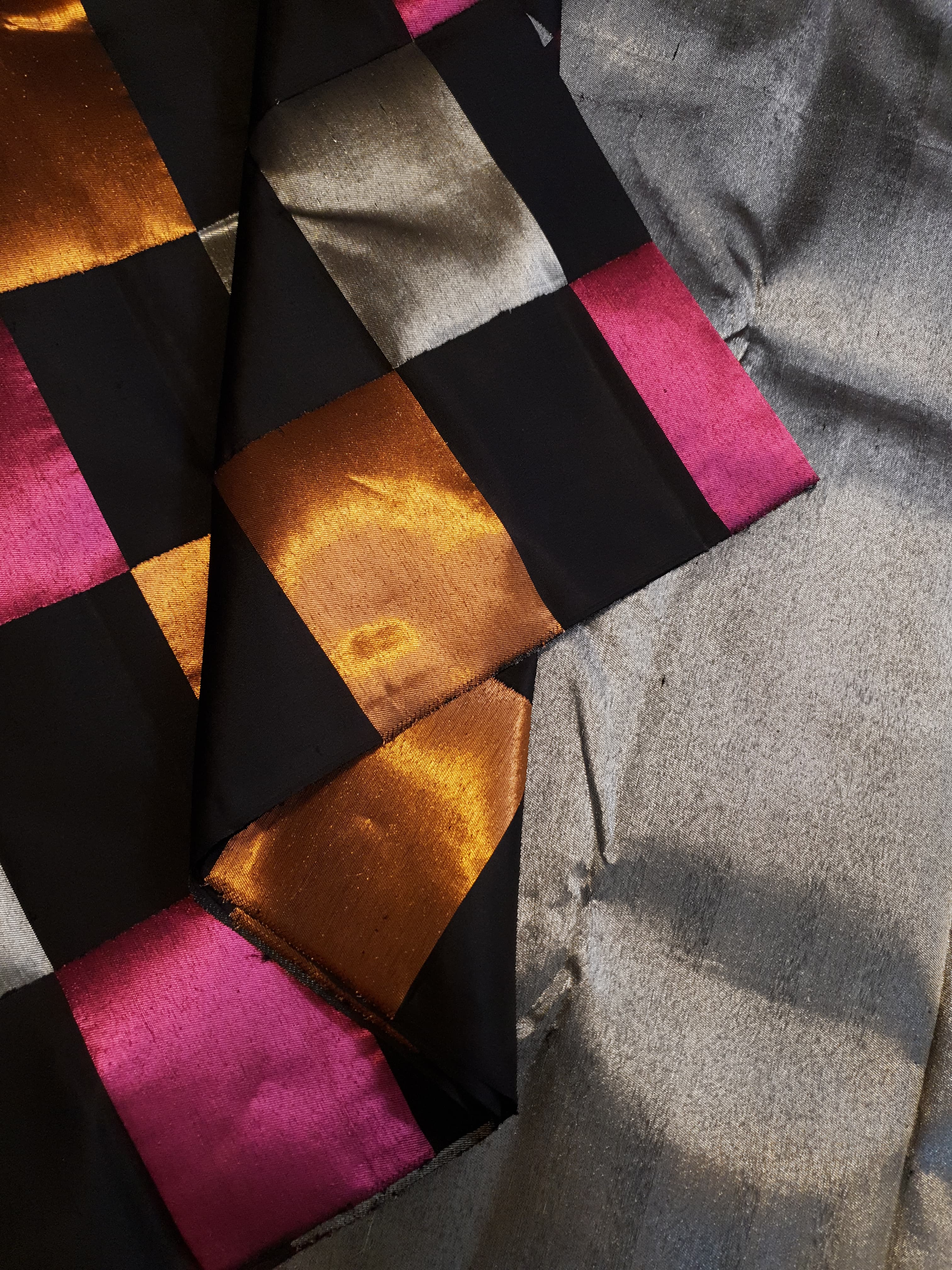 A luxurious multicolor 2G Kanchipuram pattu silk saree featuring a bold checkered pattern in black, pink, gold, and silver, displayed elegantly with traditional weaves.