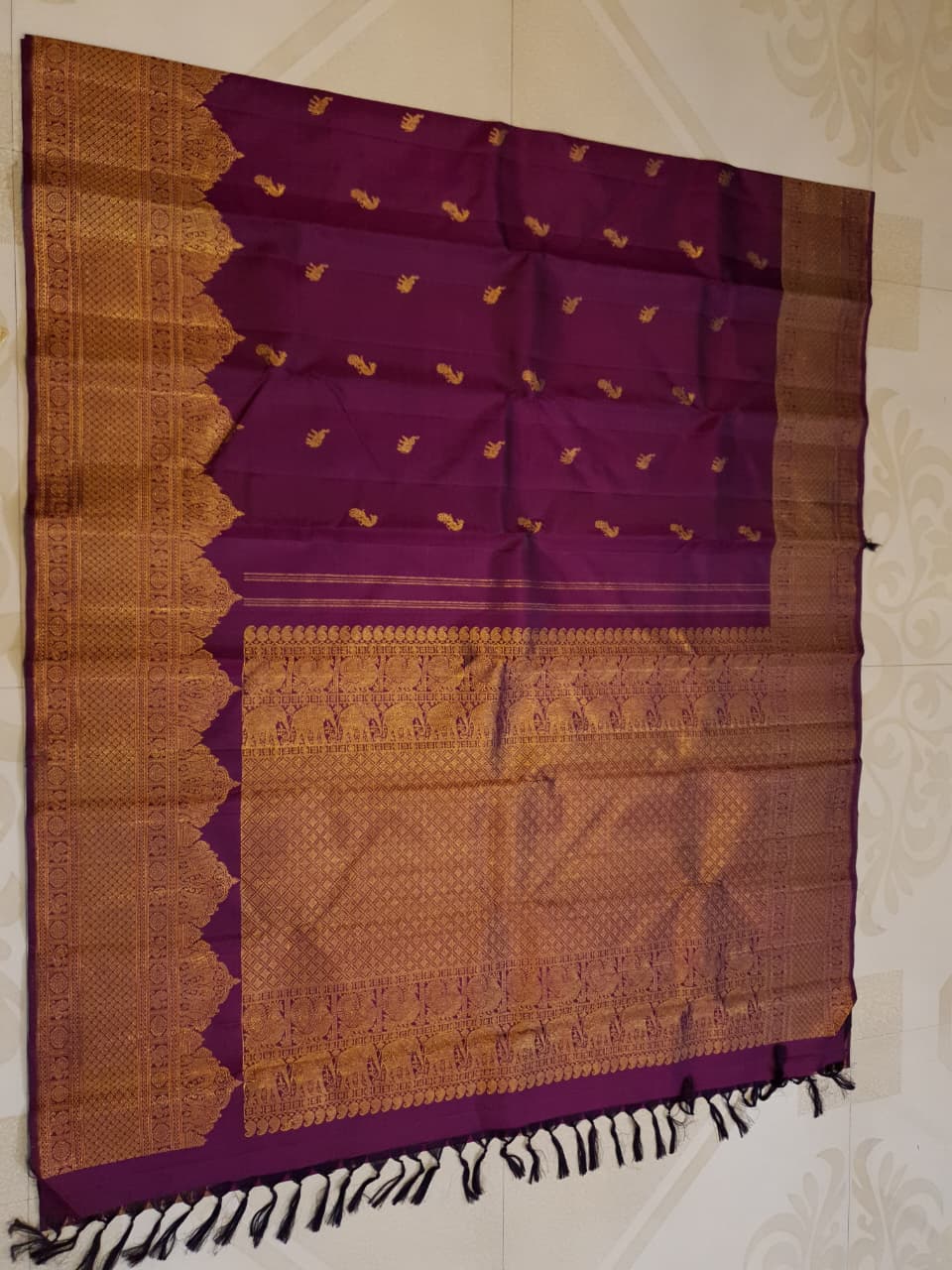 A bride in a traditional South Indian temple wears the intricate Magenta Kanchipuram Handloom 2G Gold Vairaoosi Silk Saree with matching temple jewelry.