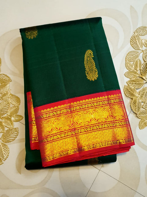 Bottle green Kanchipuram handloom Korvai silk saree, showcasing the intricate 2G gold zari motifs across the body, a vibrant contrasting pink and gold border, seamless Korvai interlocking craftsmanship, and an accompanying Silk Mark certification tag guaranteeing pure silk authenticity.