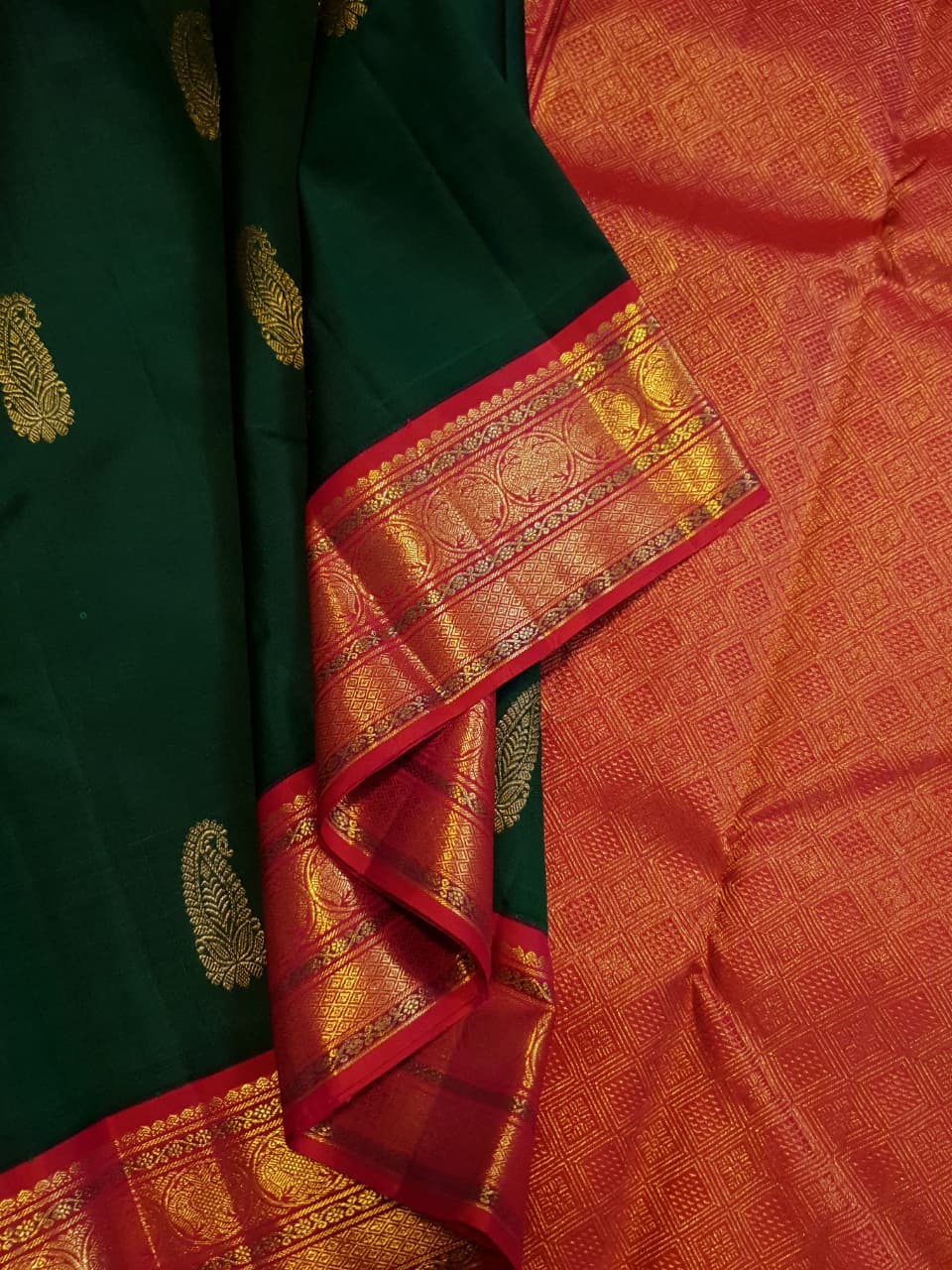 Bottle green Kanchipuram handloom Korvai silk saree, showcasing the intricate 2G gold zari motifs across the body, a vibrant contrasting pink and gold border, seamless Korvai interlocking craftsmanship, and an accompanying Silk Mark certification tag guaranteeing pure silk authenticity.