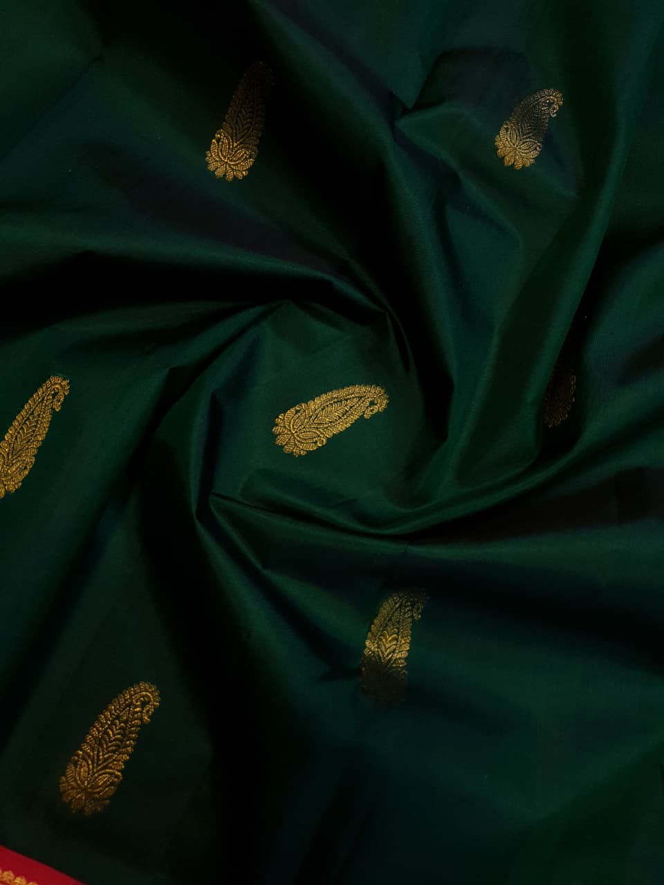 Bottle green Kanchipuram handloom Korvai silk saree, showcasing the intricate 2G gold zari motifs across the body, a vibrant contrasting pink and gold border, seamless Korvai interlocking craftsmanship, and an accompanying Silk Mark certification tag guaranteeing pure silk authenticity.