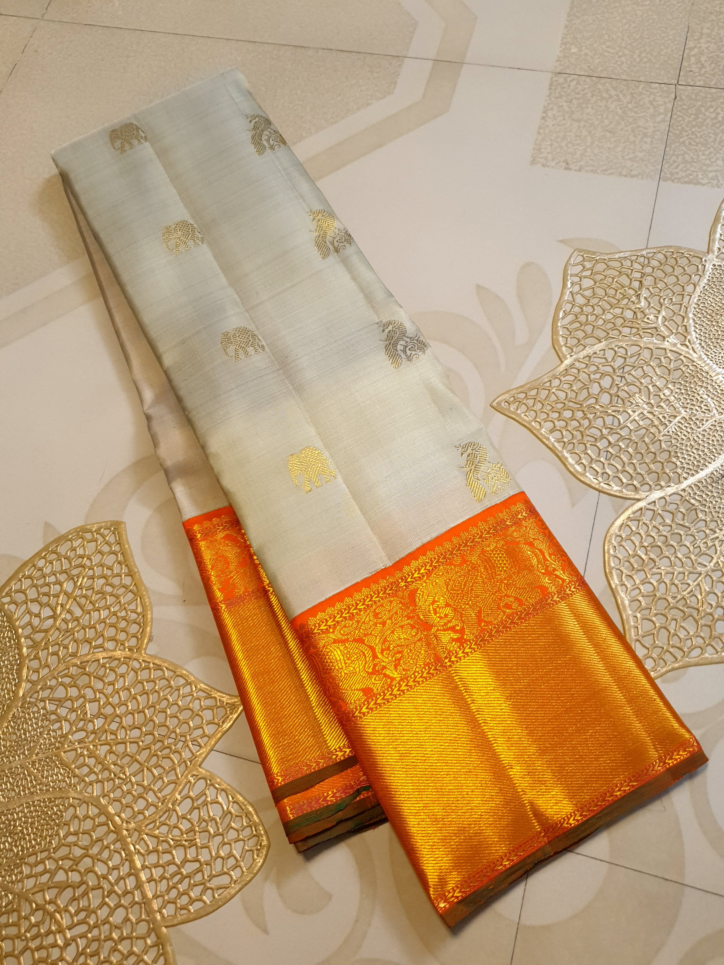Beige Kanchipuram handloom 2G gold korvai silk saree with a striking orange and gold zari border.