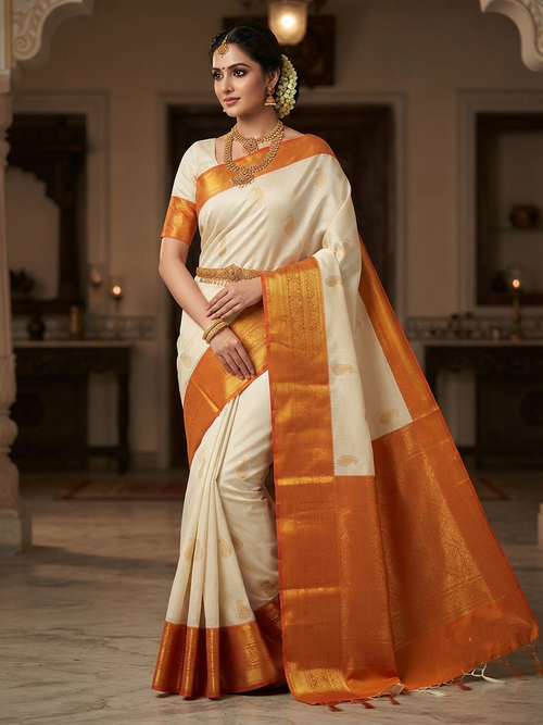 A graceful model wearing a cream and orange Kanchipuram handloom 2G gold korvai silk saree featuring traditional gold zari weaving and classic paisley buttis.