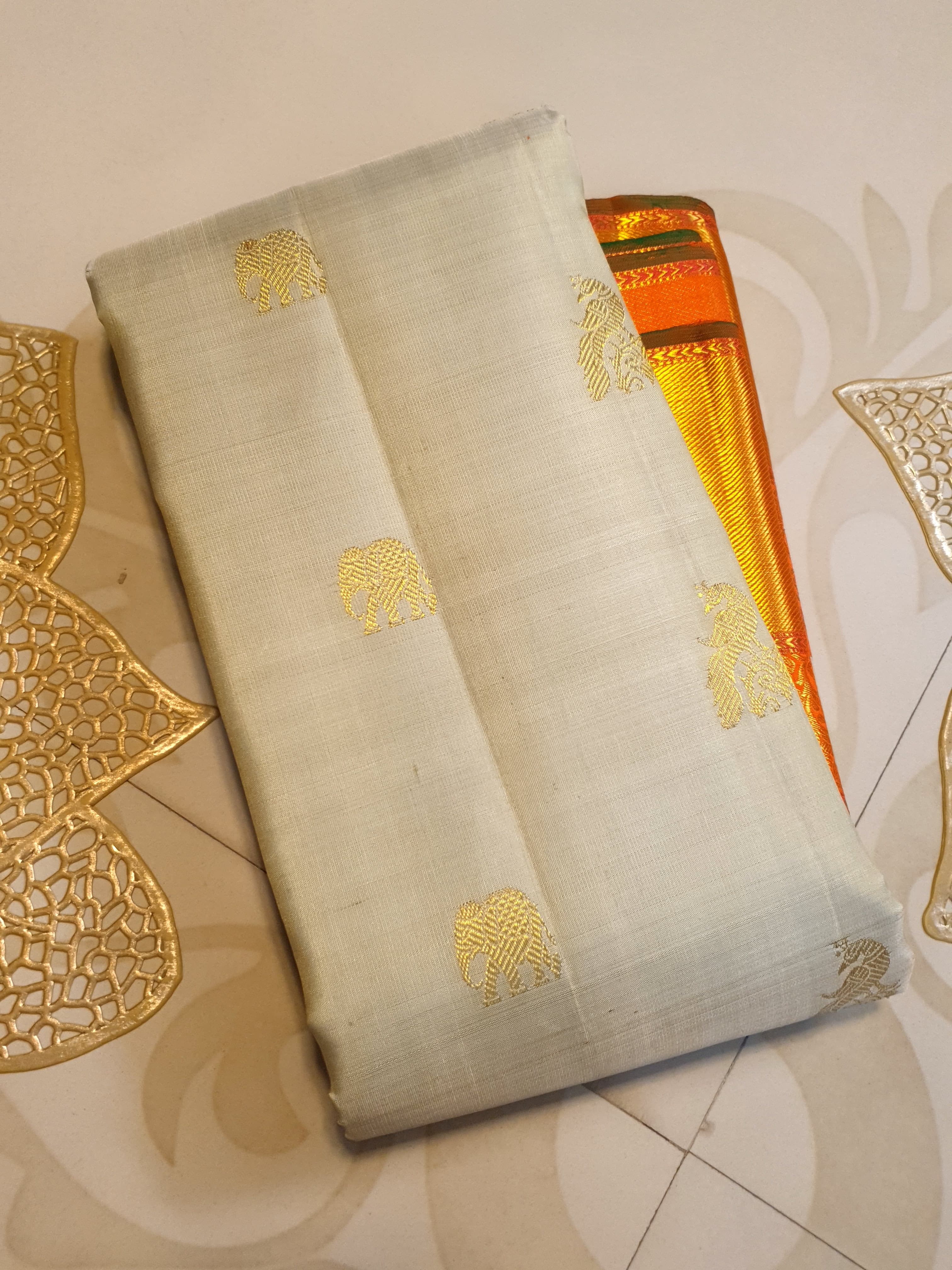 Beige Kanchipuram handloom 2G gold korvai silk saree with a striking orange and gold zari border.