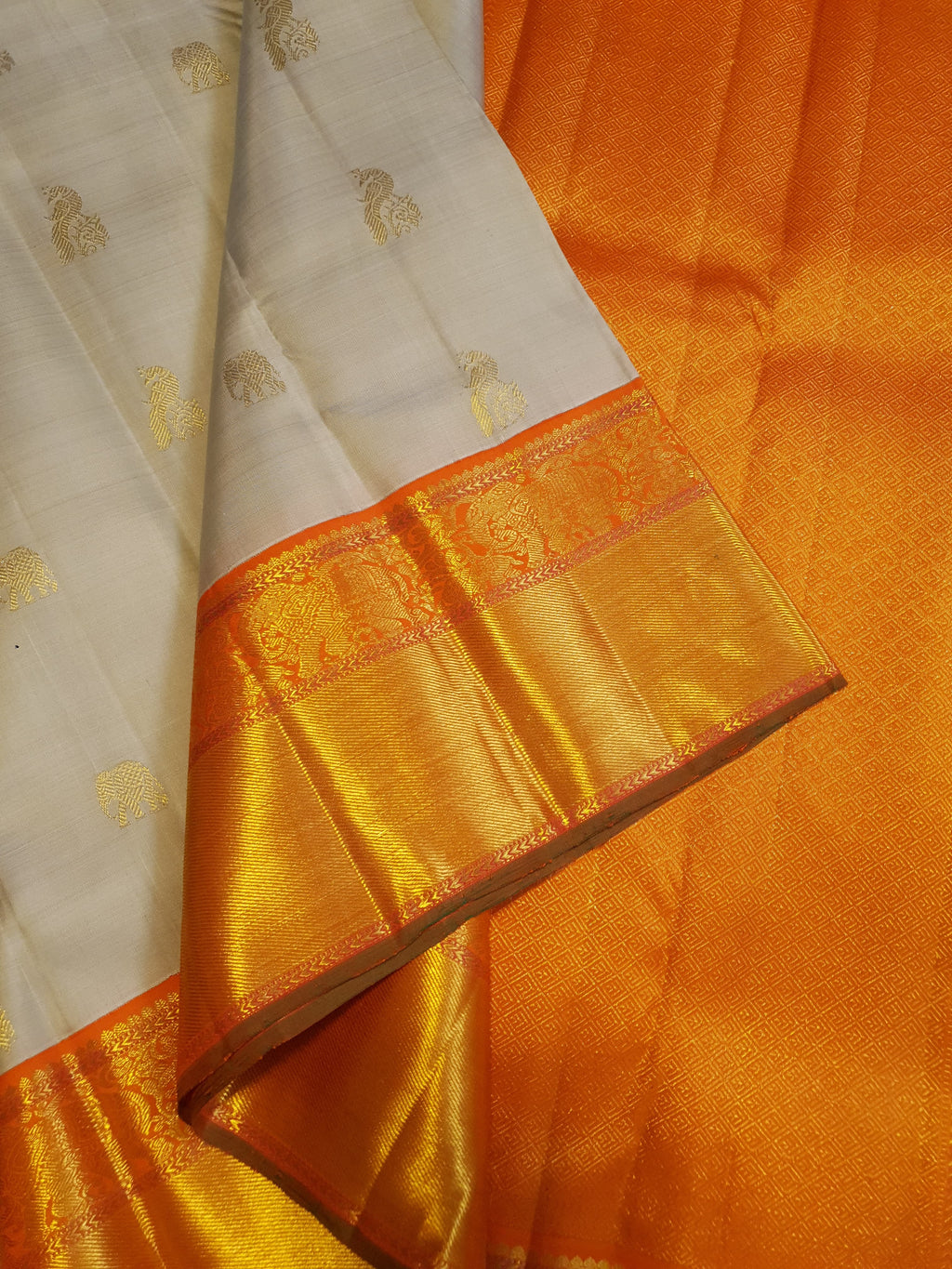 Beige Kanchipuram handloom 2G gold korvai silk saree with a striking orange and gold zari border.