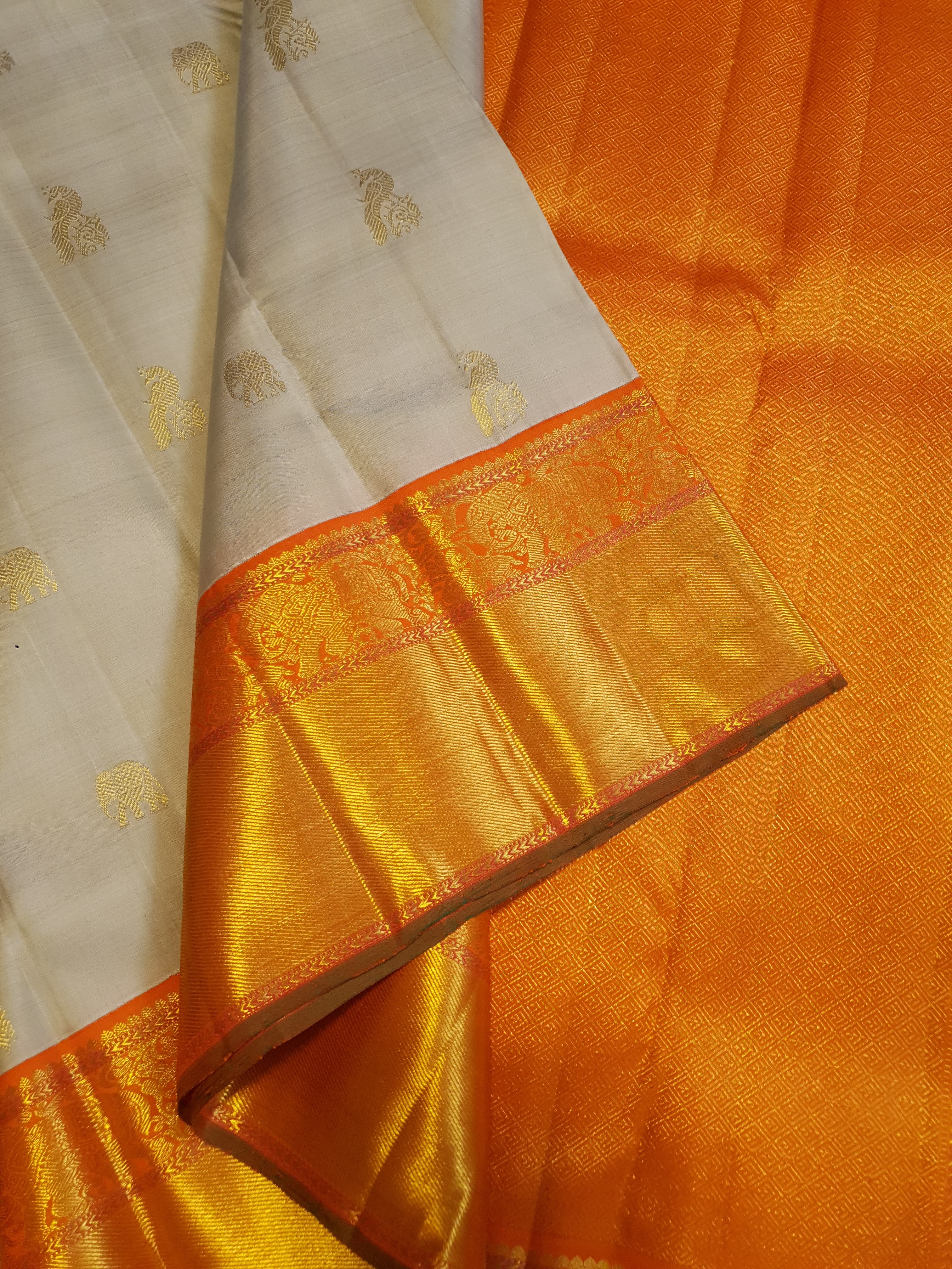 Beige Kanchipuram handloom 2G gold korvai silk saree with a striking orange and gold zari border.