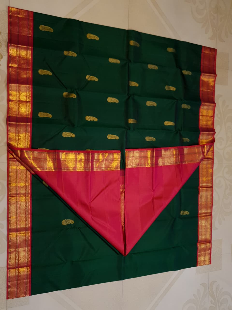 Bottle green Kanchipuram handloom Korvai silk saree, showcasing the intricate 2G gold zari motifs across the body, a vibrant contrasting pink and gold border, seamless Korvai interlocking craftsmanship, and an accompanying Silk Mark certification tag guaranteeing pure silk authenticity.