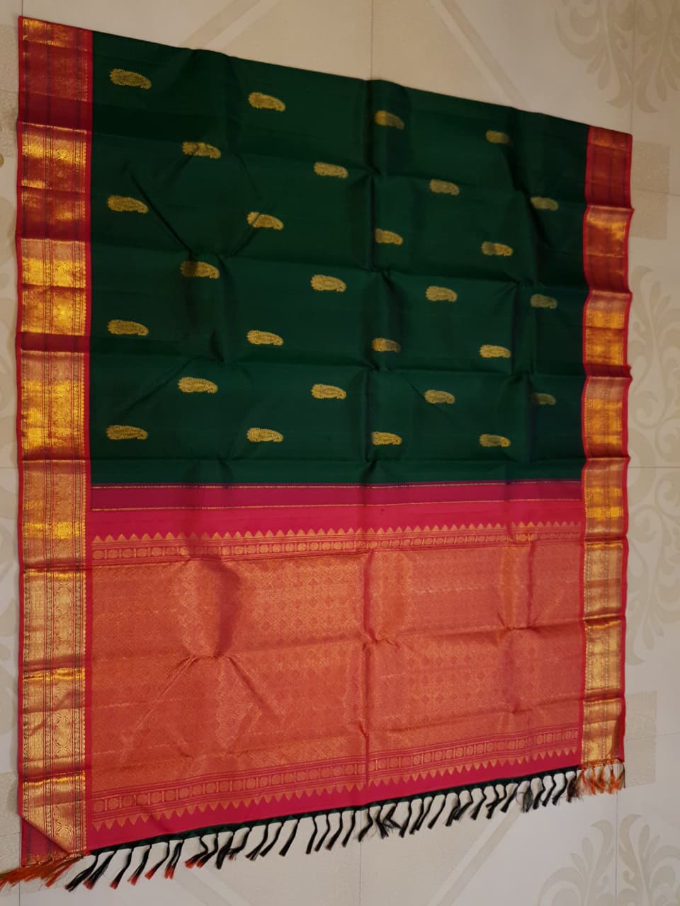 Bottle green Kanchipuram handloom Korvai silk saree, showcasing the intricate 2G gold zari motifs across the body, a vibrant contrasting pink and gold border, seamless Korvai interlocking craftsmanship, and an accompanying Silk Mark certification tag guaranteeing pure silk authenticity.