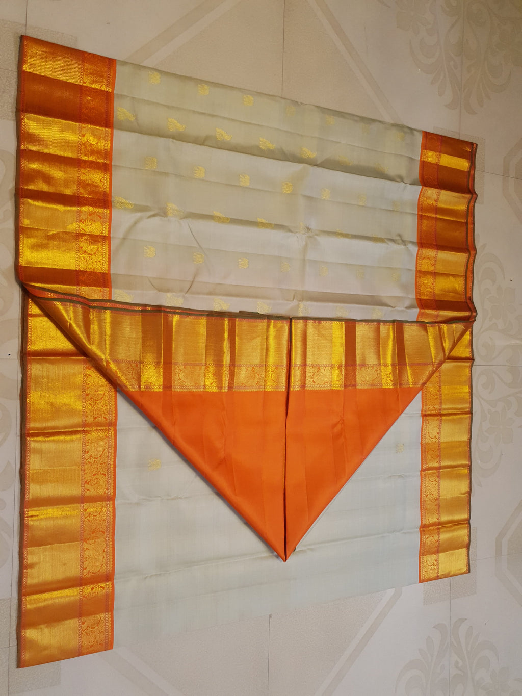 Beige Kanchipuram handloom 2G gold korvai silk saree with a striking orange and gold zari border.