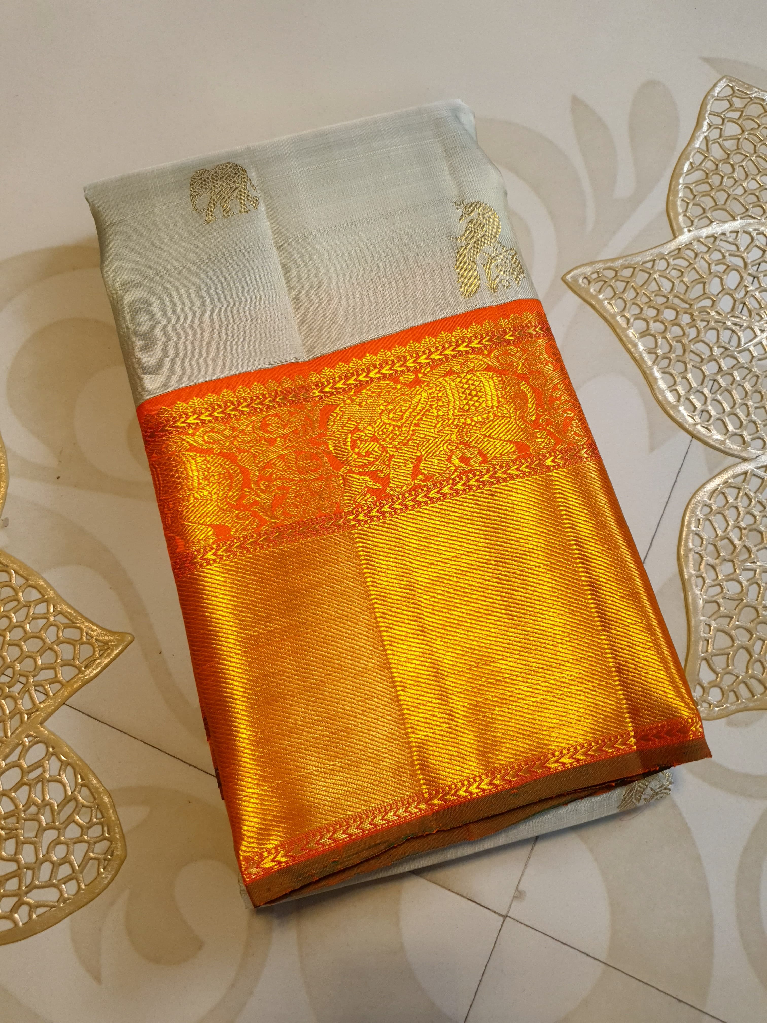 Beige Kanchipuram handloom 2G gold korvai silk saree with a striking orange and gold zari border.