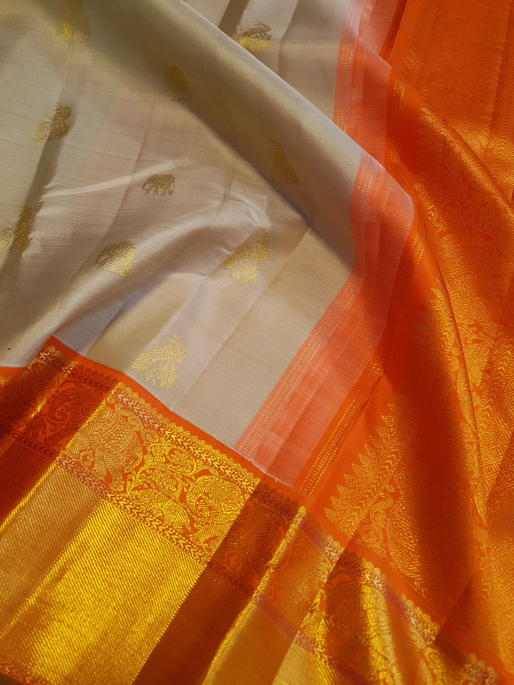 Beige Kanchipuram handloom 2G gold korvai silk saree with a striking orange and gold zari border.