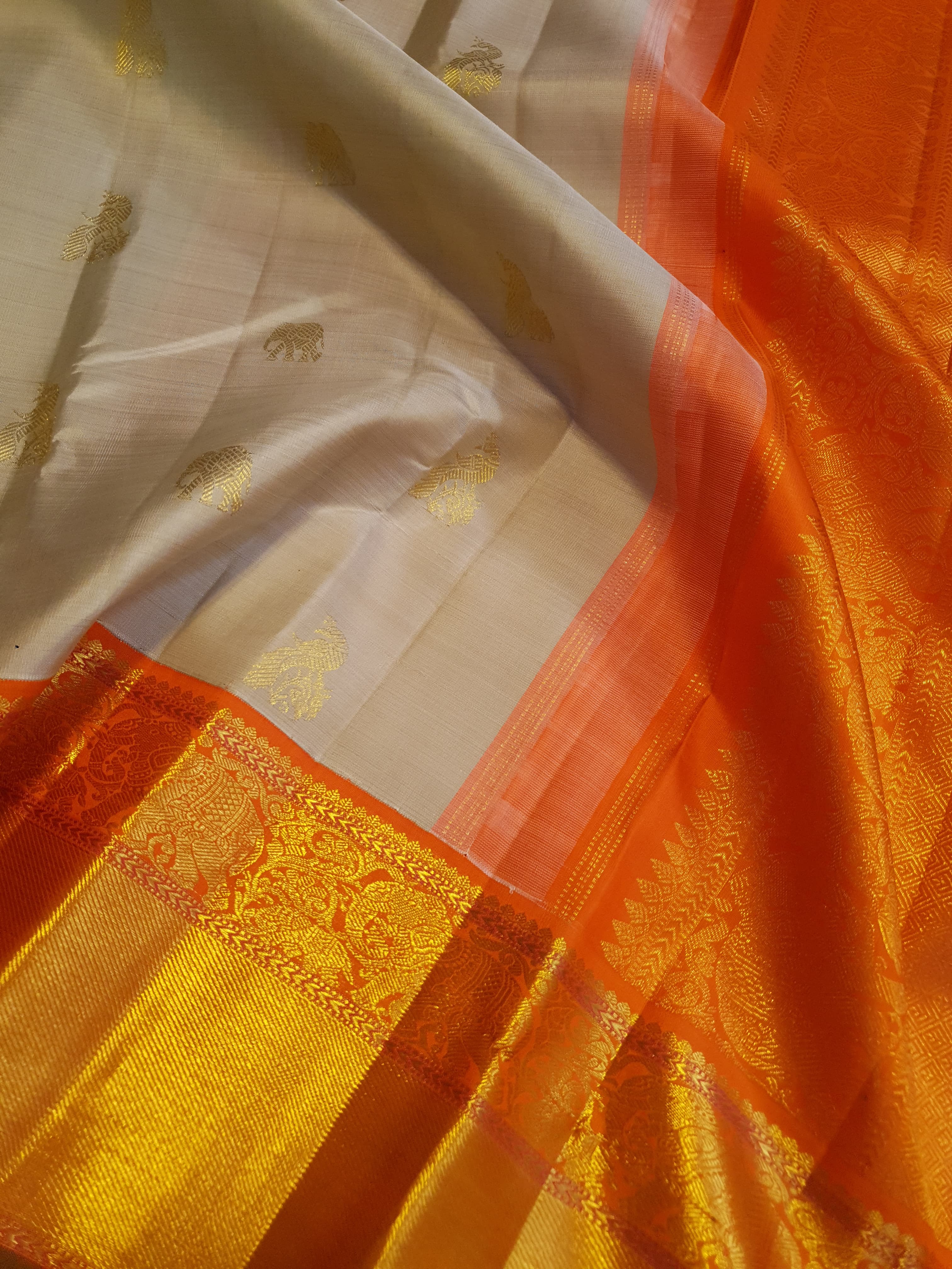 Beige Kanchipuram handloom 2G gold korvai silk saree with a striking orange and gold zari border.