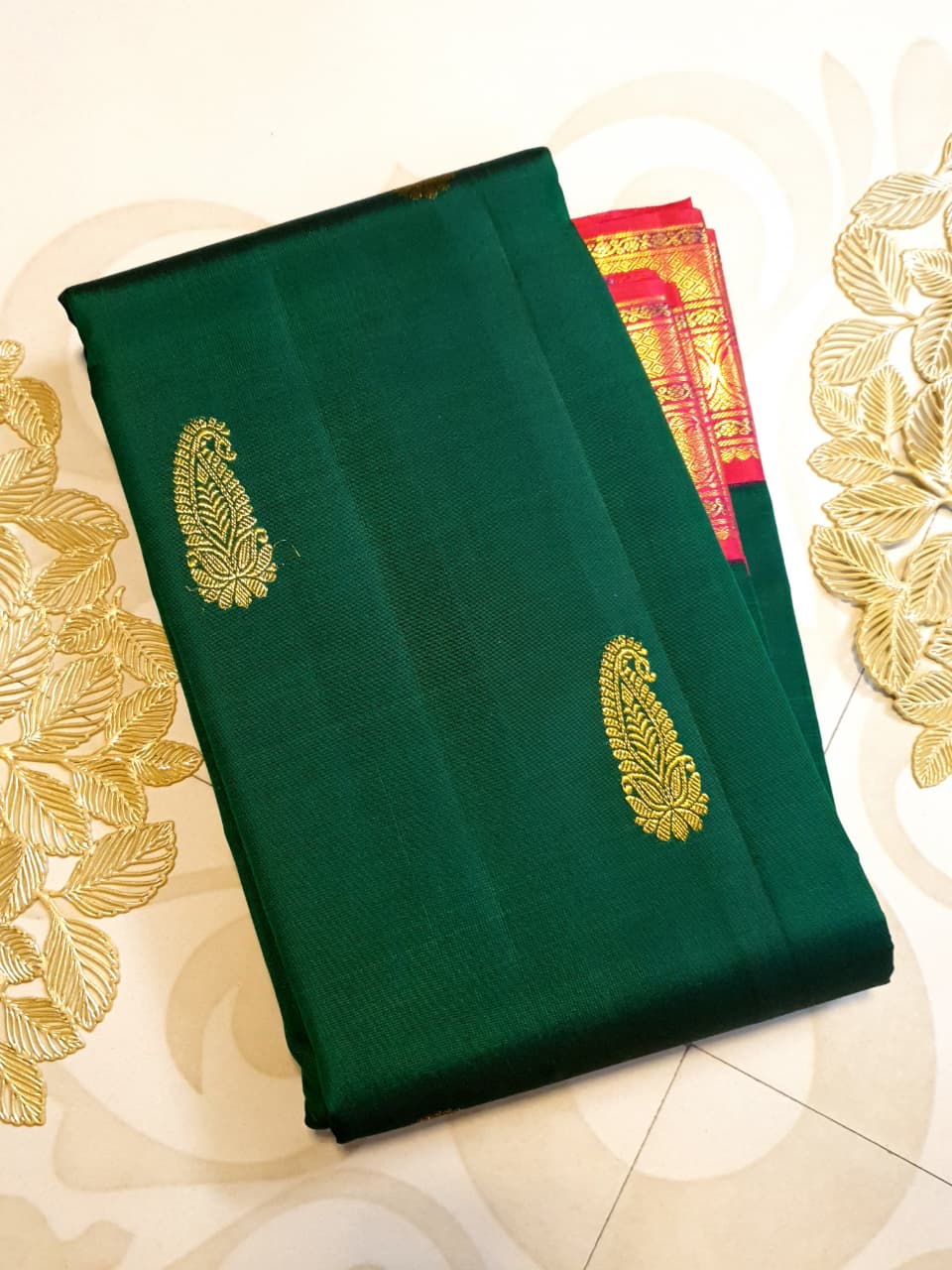 Bottle green Kanchipuram handloom Korvai silk saree, showcasing the intricate 2G gold zari motifs across the body, a vibrant contrasting pink and gold border, seamless Korvai interlocking craftsmanship, and an accompanying Silk Mark certification tag guaranteeing pure silk authenticity.
