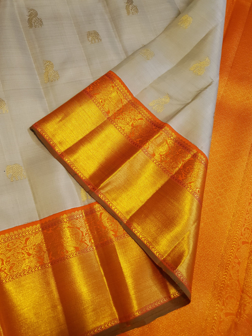 Beige Kanchipuram handloom 2G gold korvai silk saree with a striking orange and gold zari border.