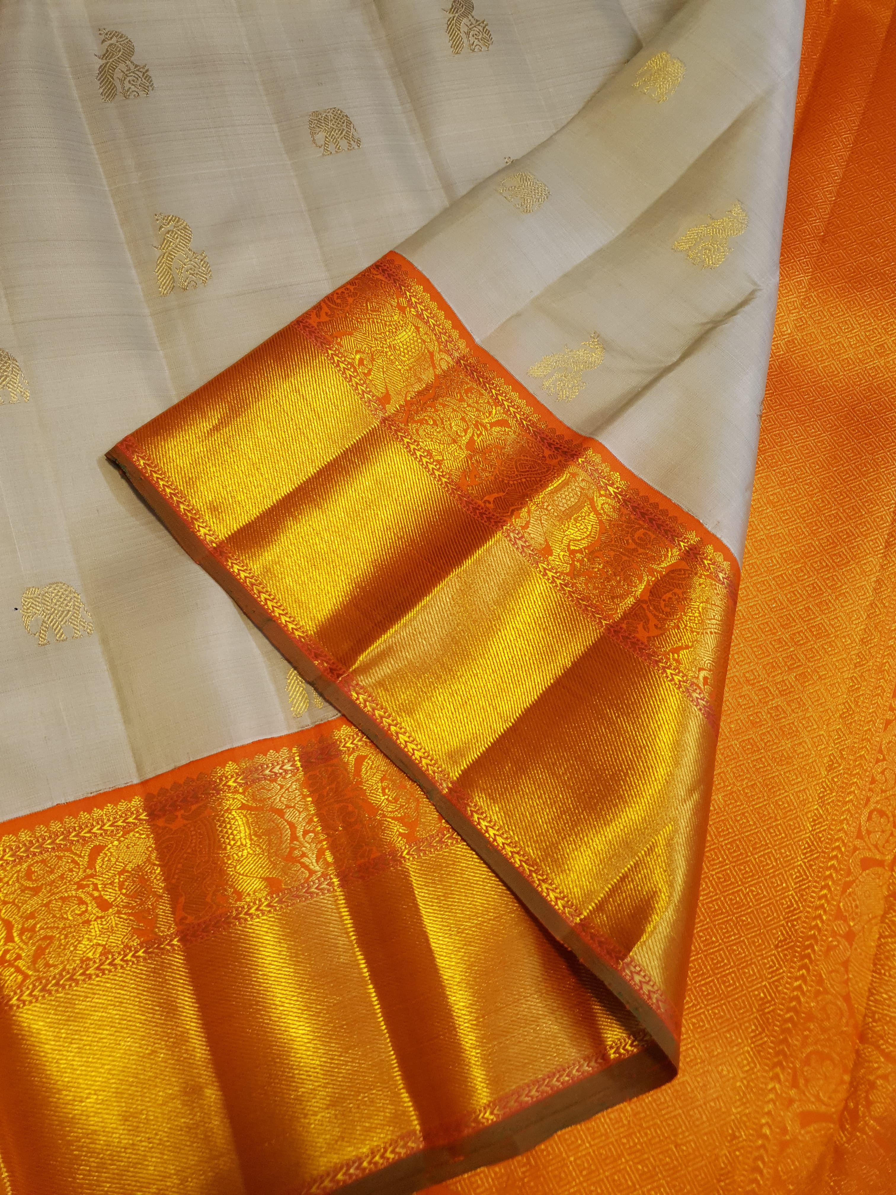 Beige Kanchipuram handloom 2G gold korvai silk saree with a striking orange and gold zari border.