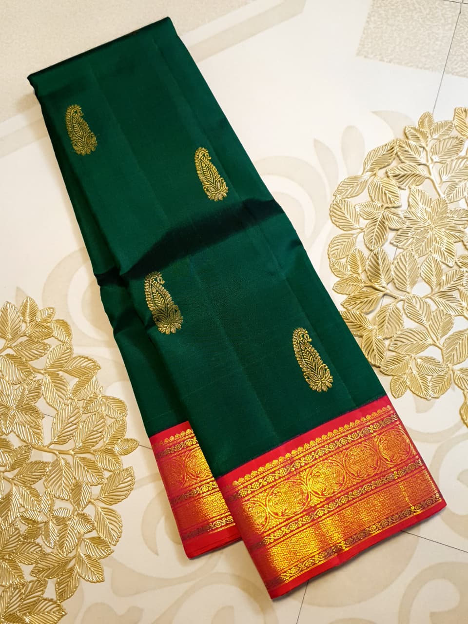 Bottle green Kanchipuram handloom Korvai silk saree, showcasing the intricate 2G gold zari motifs across the body, a vibrant contrasting pink and gold border, seamless Korvai interlocking craftsmanship, and an accompanying Silk Mark certification tag guaranteeing pure silk authenticity.