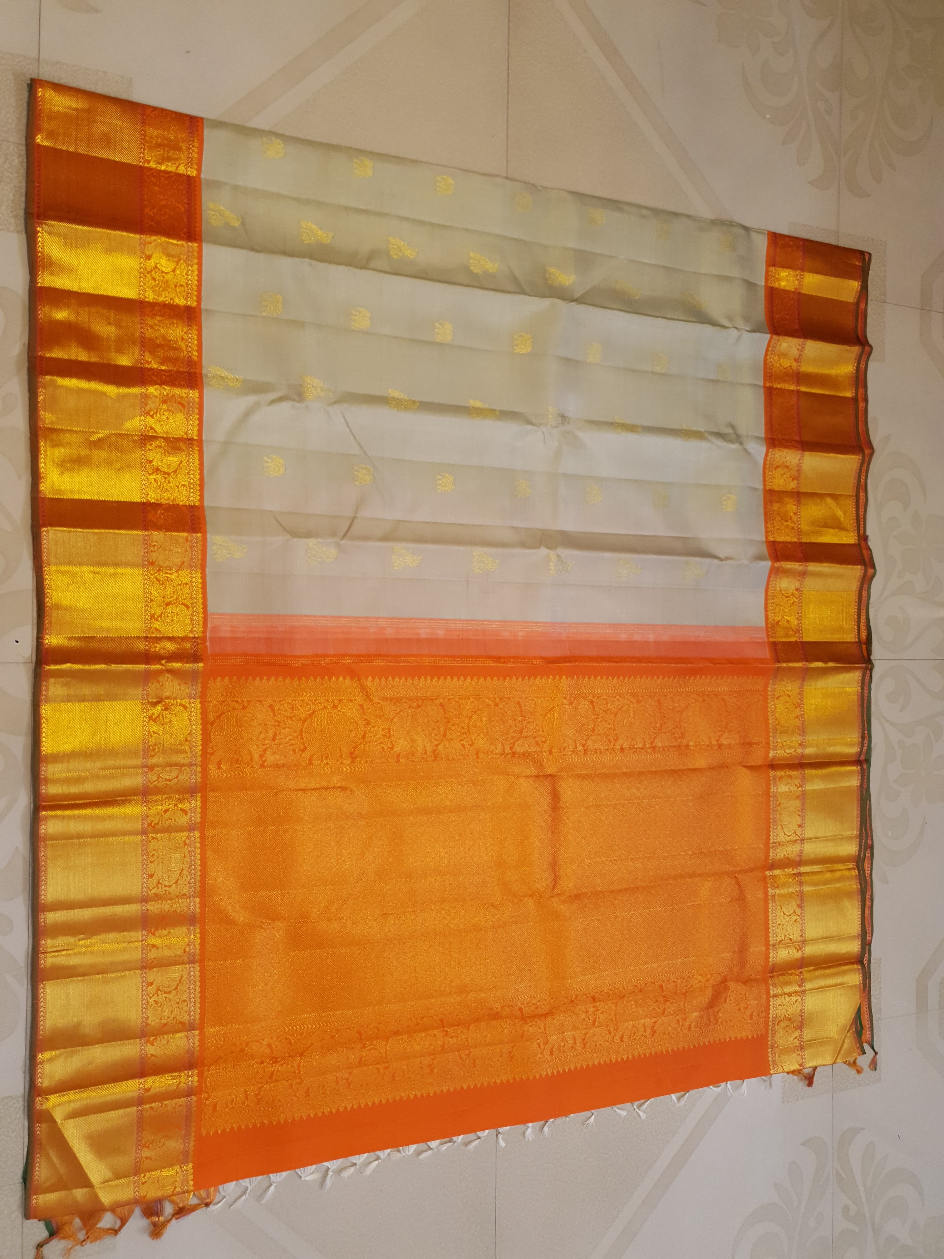 Beige Kanchipuram handloom 2G gold korvai silk saree with a striking orange and gold zari border.