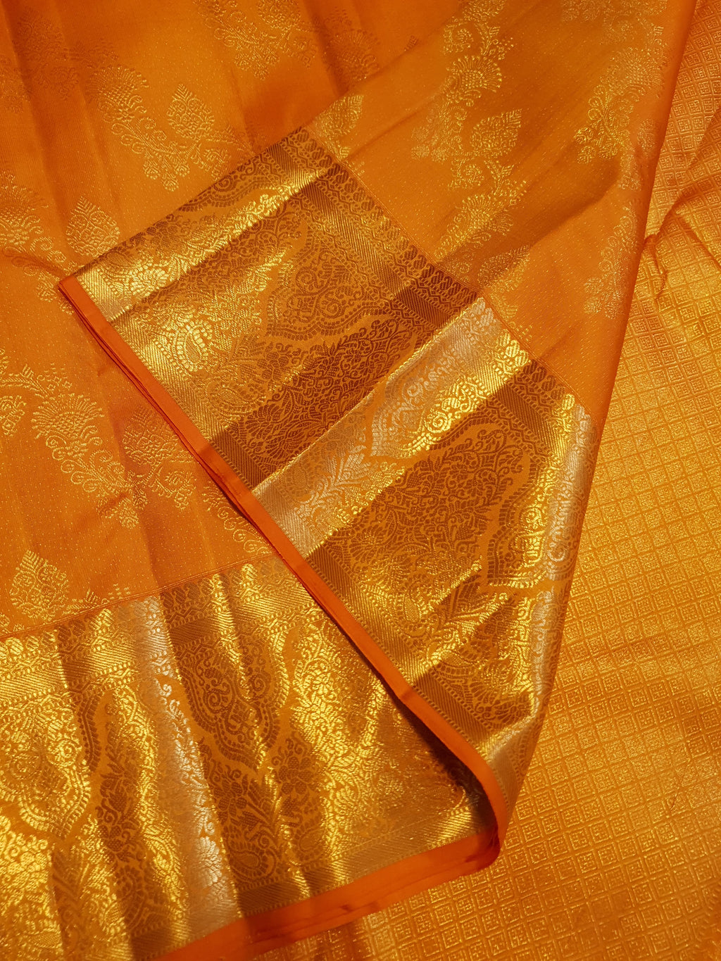 Exquisite Orange Kanchipuram handloom silk saree with intricate gold zari detailing, styled for a traditional wedding look.
